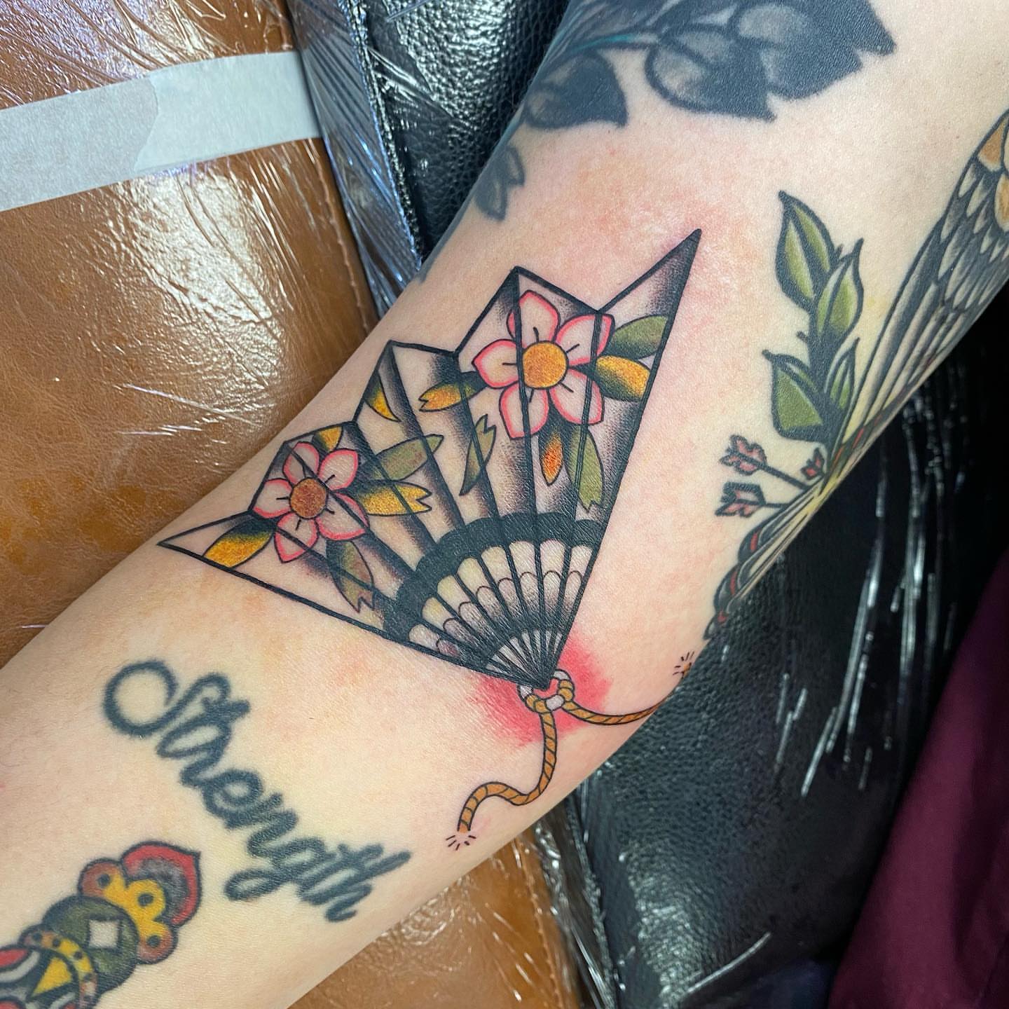 Fan and flowers American traditional tattoo on the forearm by S C O T T