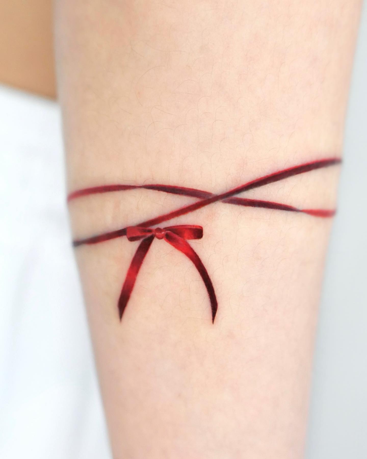 Red ribbon bow realism tattoo on the forearm by Cyber sigil & ornamental tattoo π₯