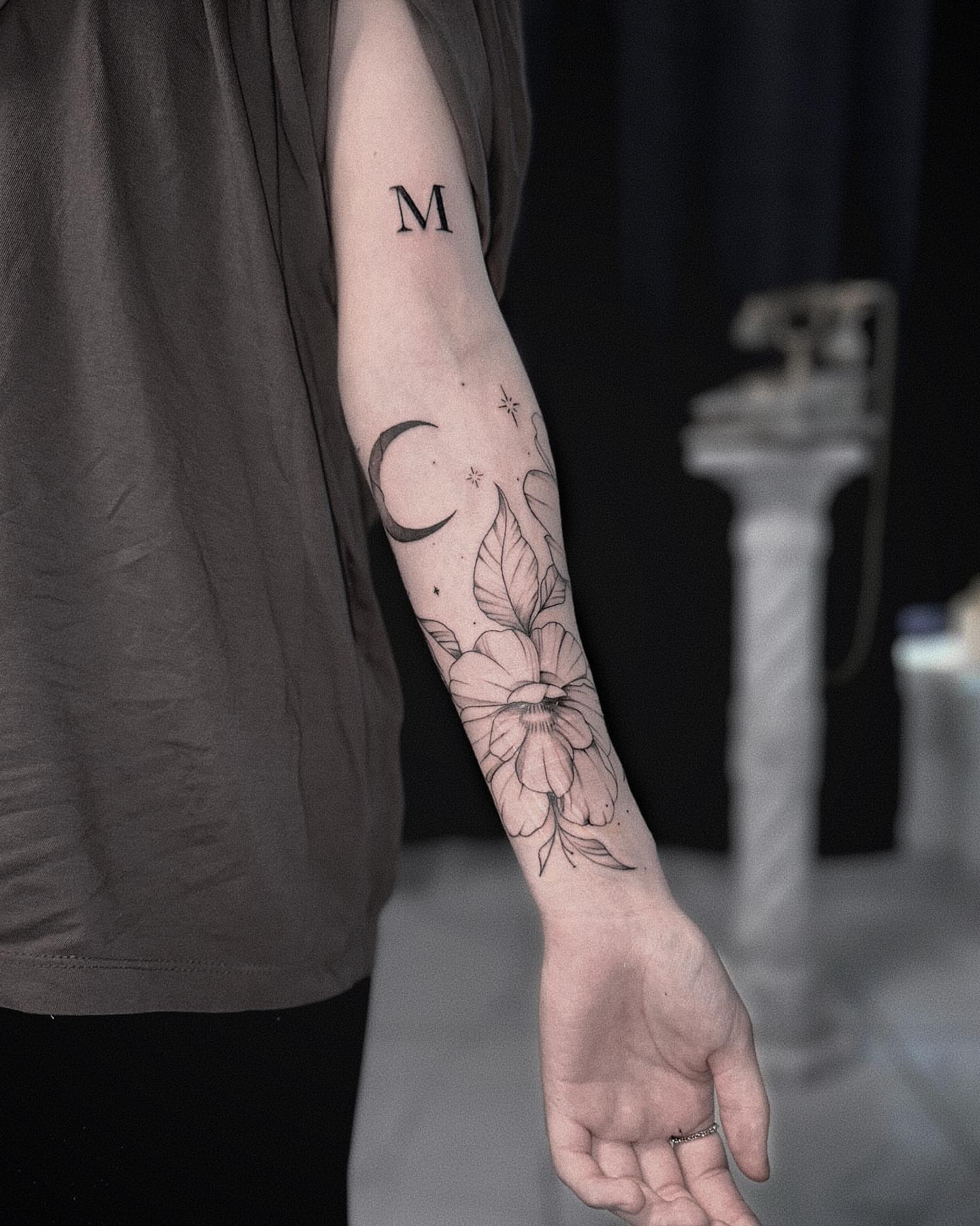 Flower and crescent moon black and grey tattoo on the forearm by Ron Alvarez