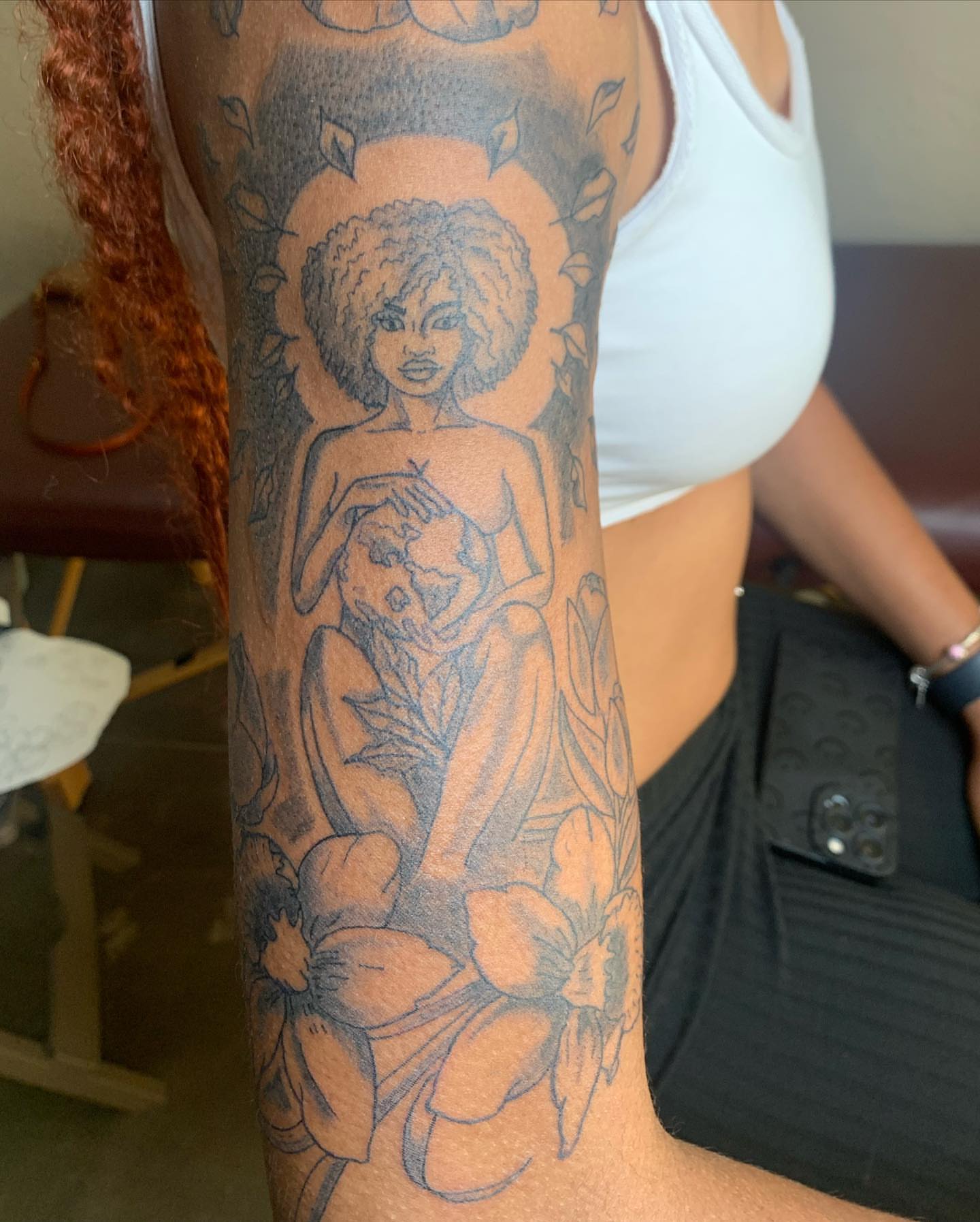 Woman with afro black and grey tattoo on the forearm by Evan Chastain