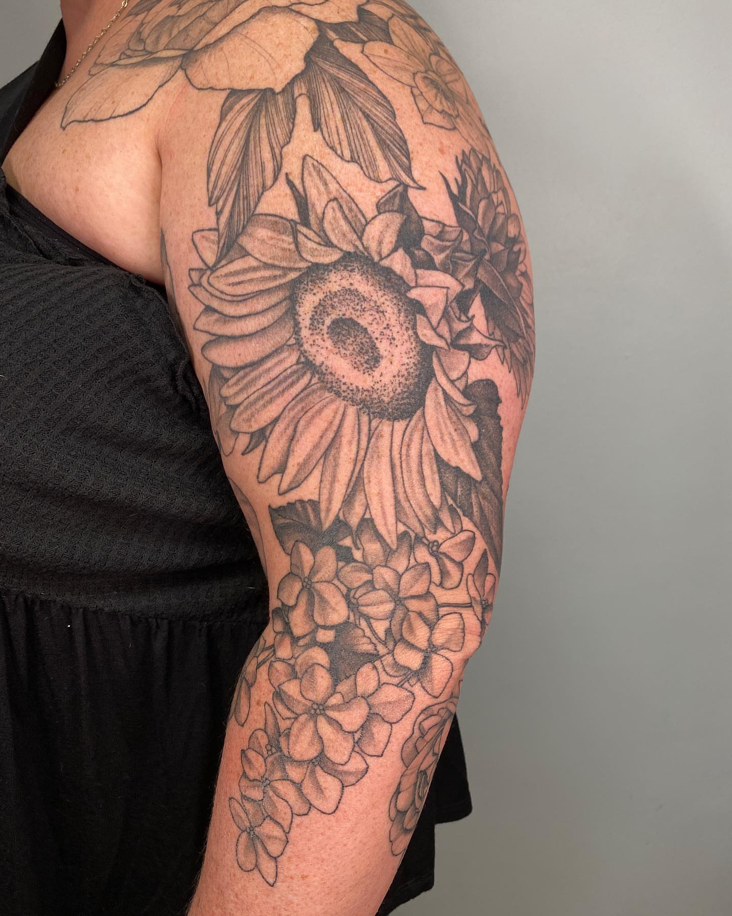 Sunflower and flowers dotwork tattoo on the upper arm by Tattoo Artist