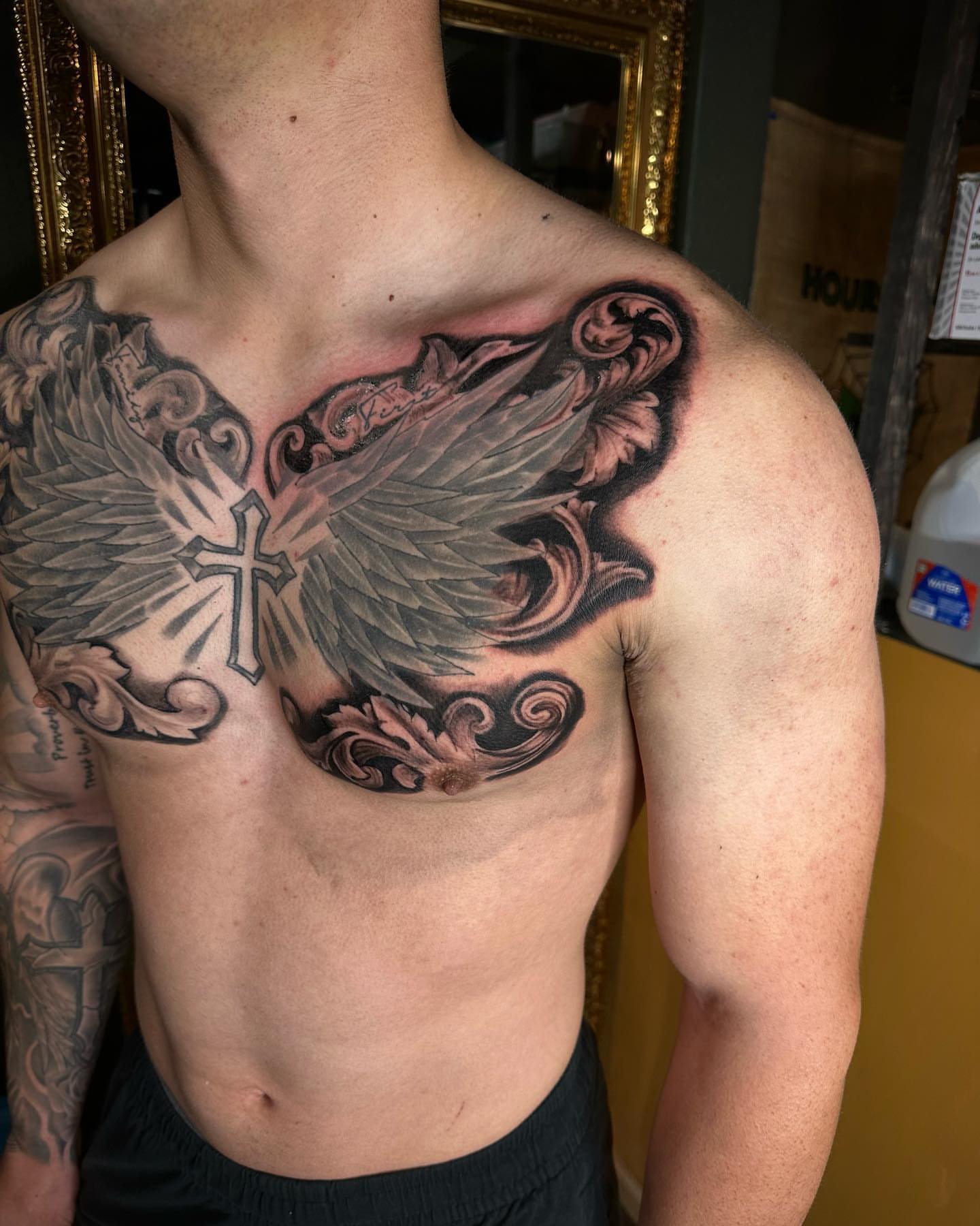 Wings and cross realism tattoo on the chest by Leo Torres