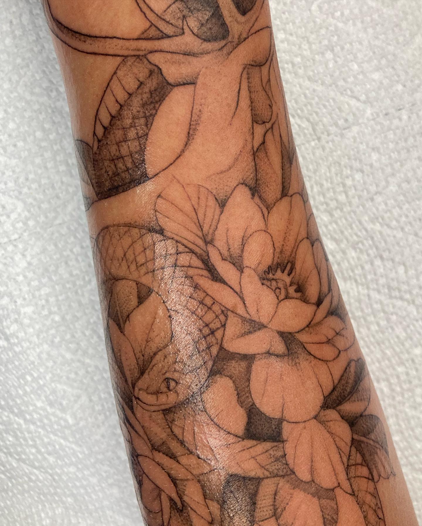 Snake and flowers black and grey tattoo on the forearm by Hali Larkin