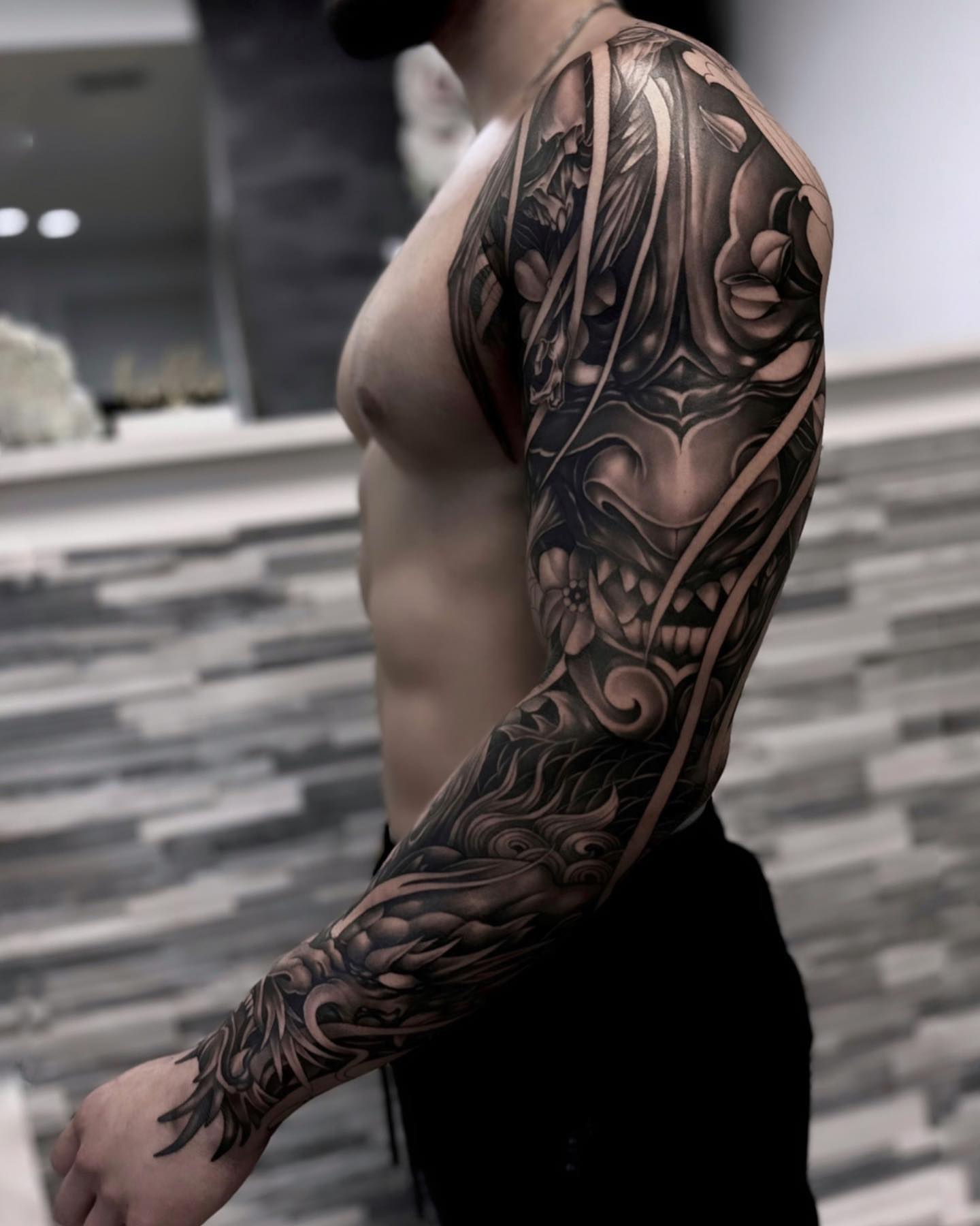 Mask and floral patterns geometric tattoo on the upper arm by Jennal Wang