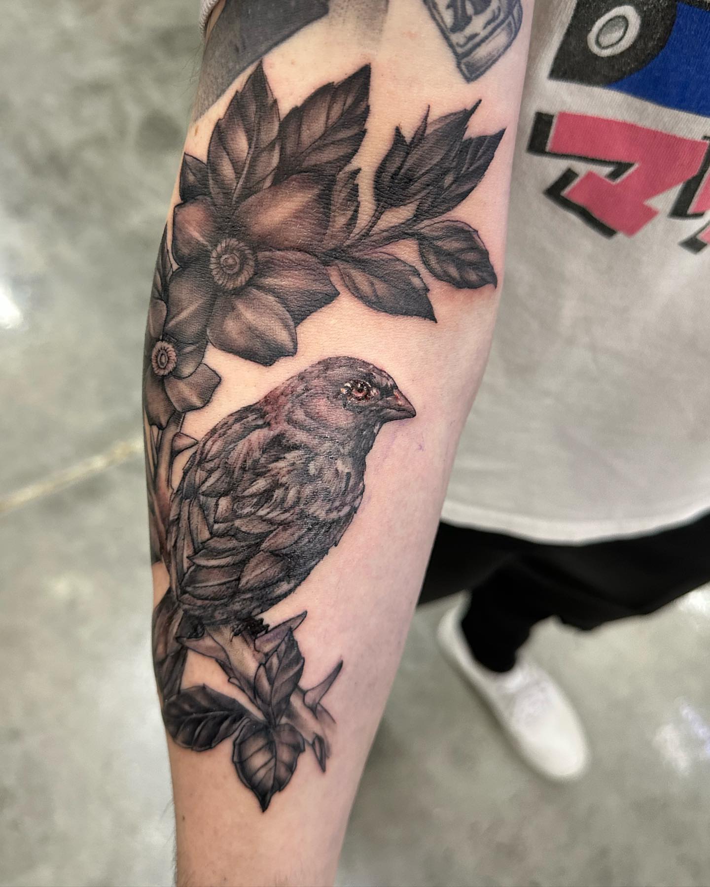 Bird and flowers realism tattoo on the forearm by Angel Gonzalez