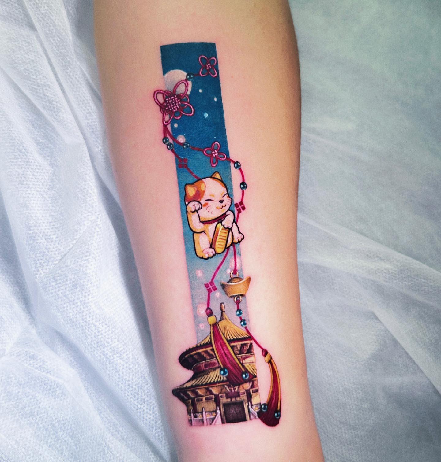 Cat and pagoda illustrative tattoo on the forearm by Eva Liu