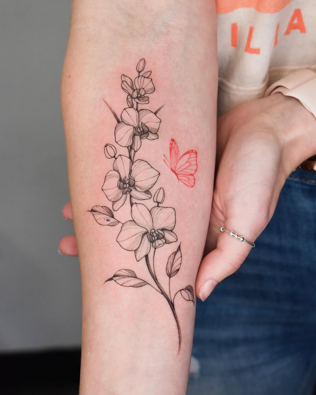 Orchid branch and butterfly fine line tattoo on the forearm by ๐๐๐ฆ ๐๐ ๐ฎ๐ฒ๐๐ง