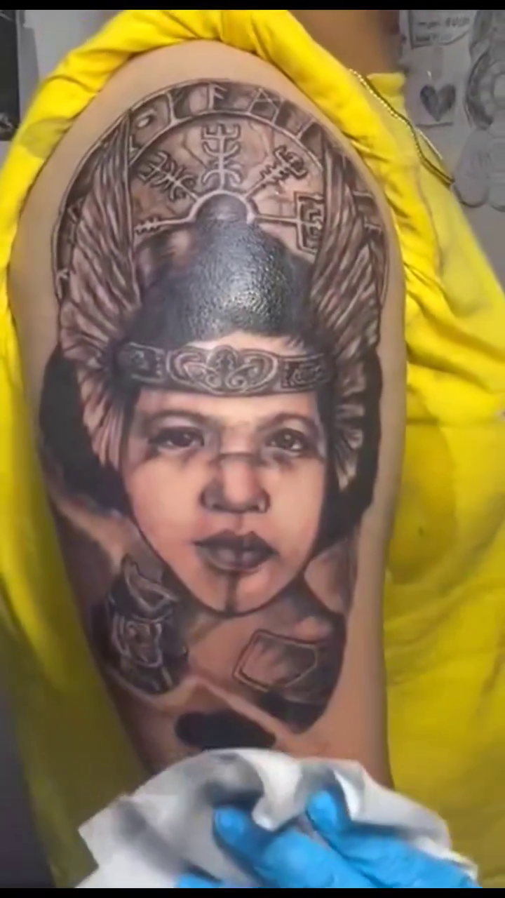 Portrait of a woman with headdress realism tattoo on the upper arm by Ferds Villanueva