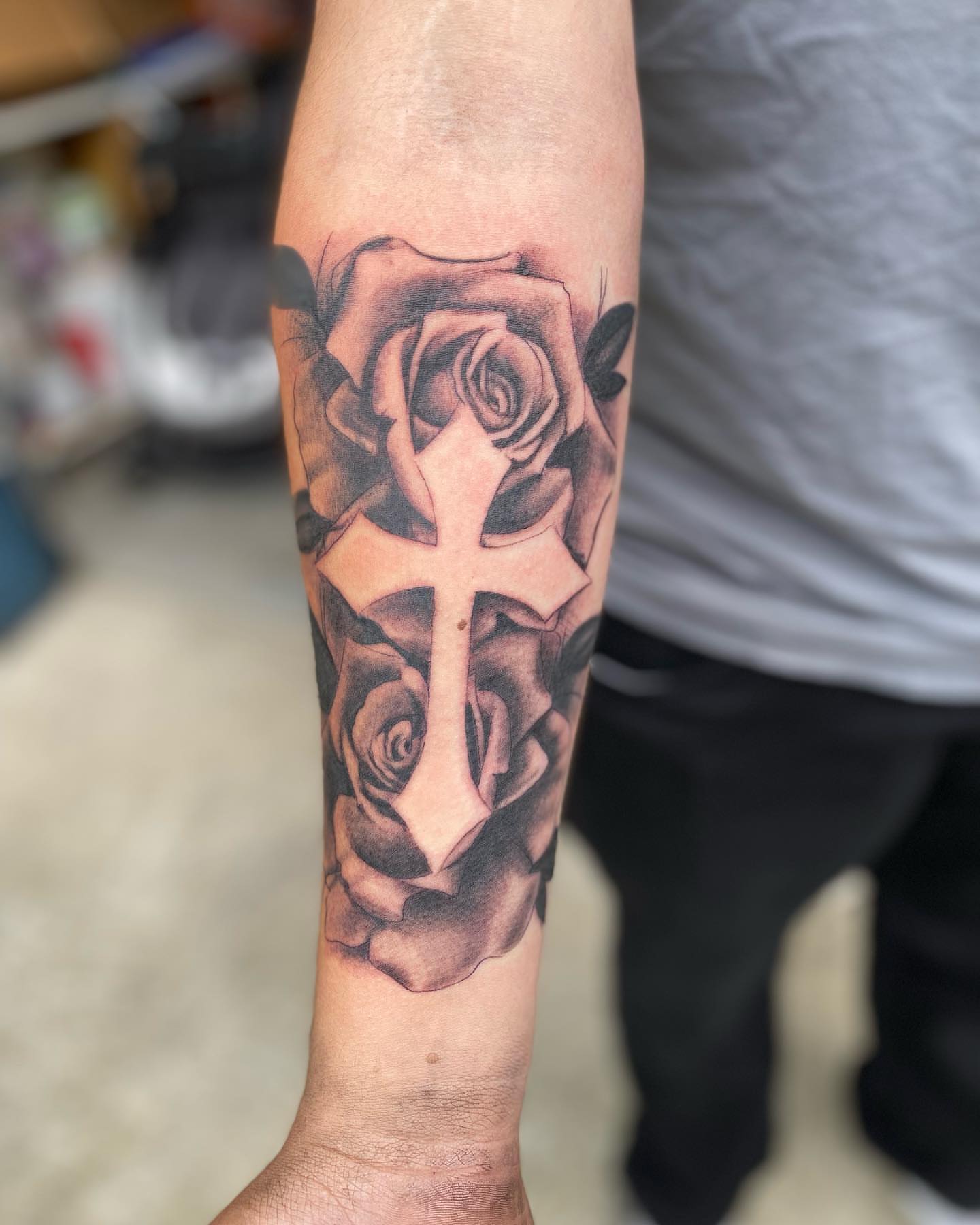 Cross and roses realism tattoo on the forearm by Chino's Tattoos