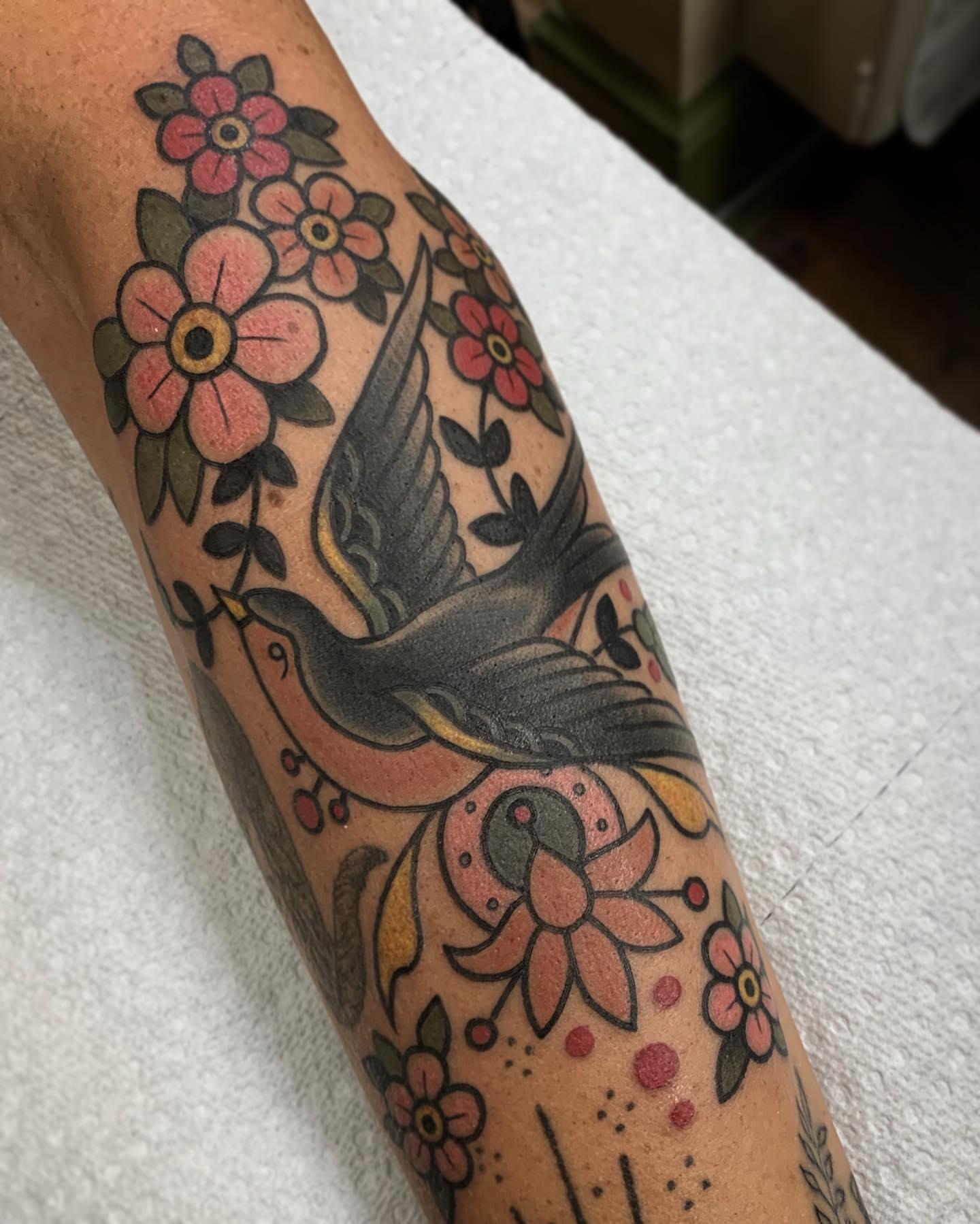 Bird and floral American traditional tattoo on the forearm by Pat Moser