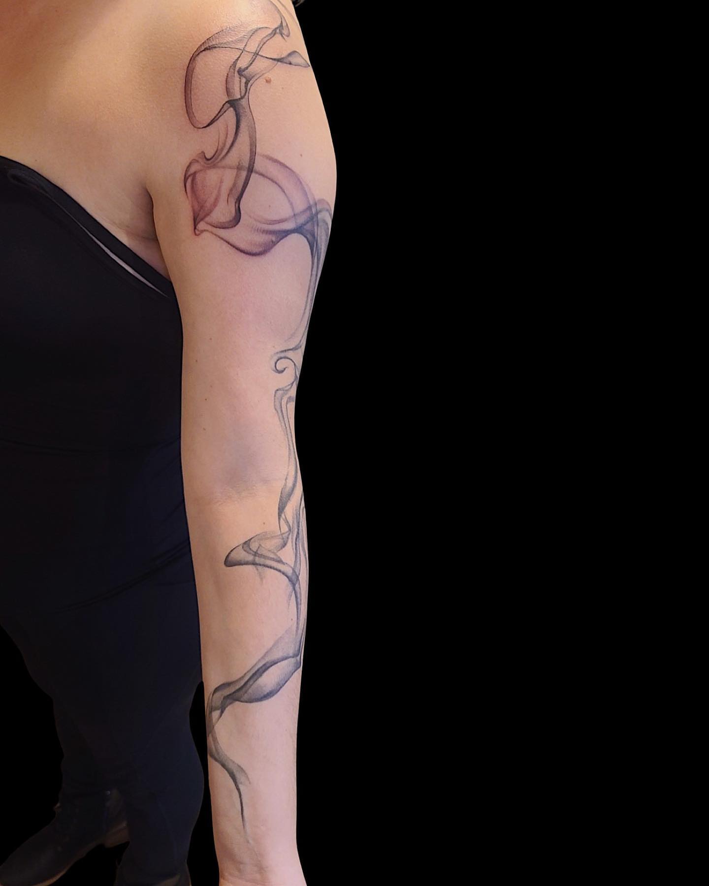 Smoke black and grey tattoo on the upper arm by Rain Delmar