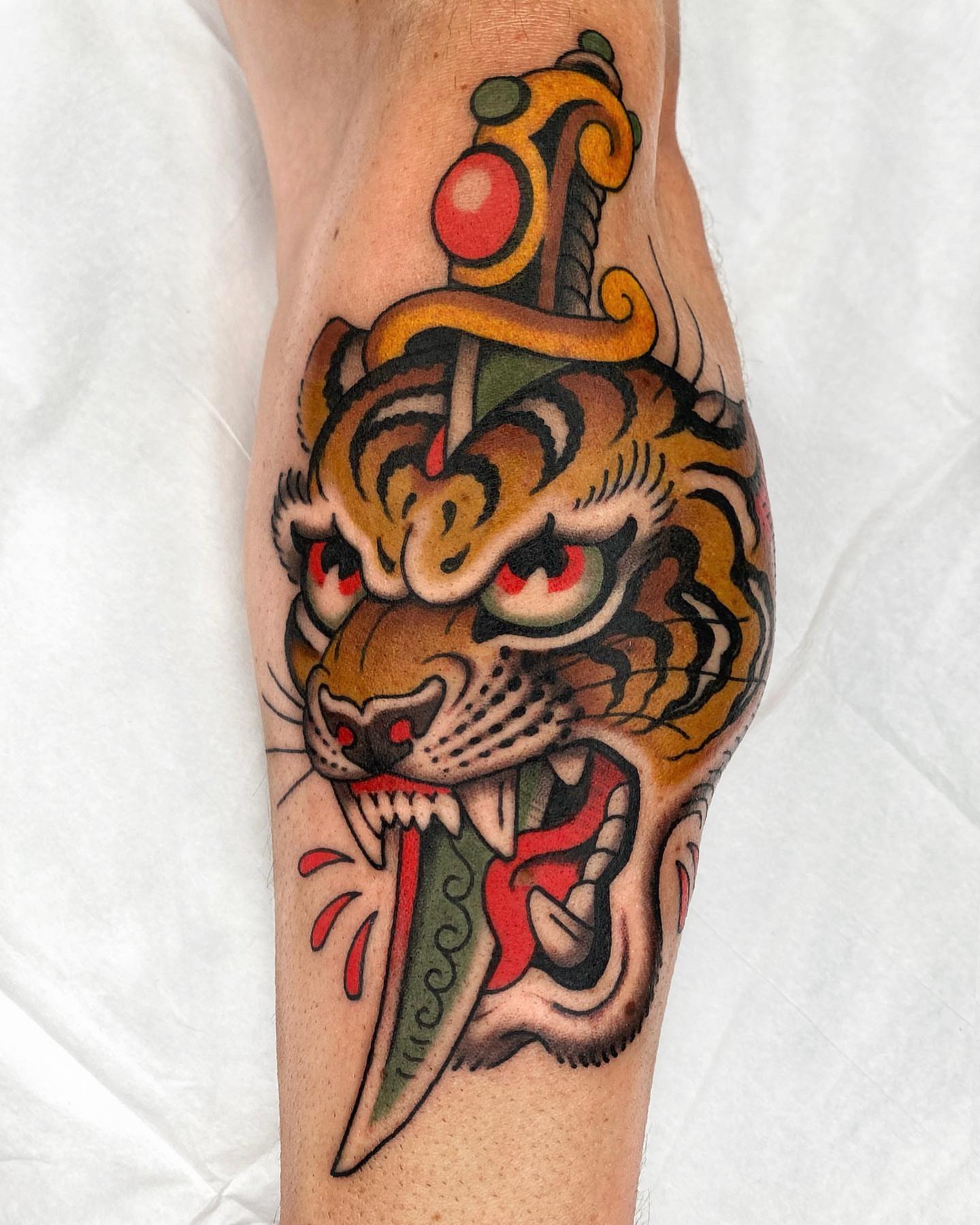 Tiger head with sword American traditional tattoo on the forearm by Wes Hoffman