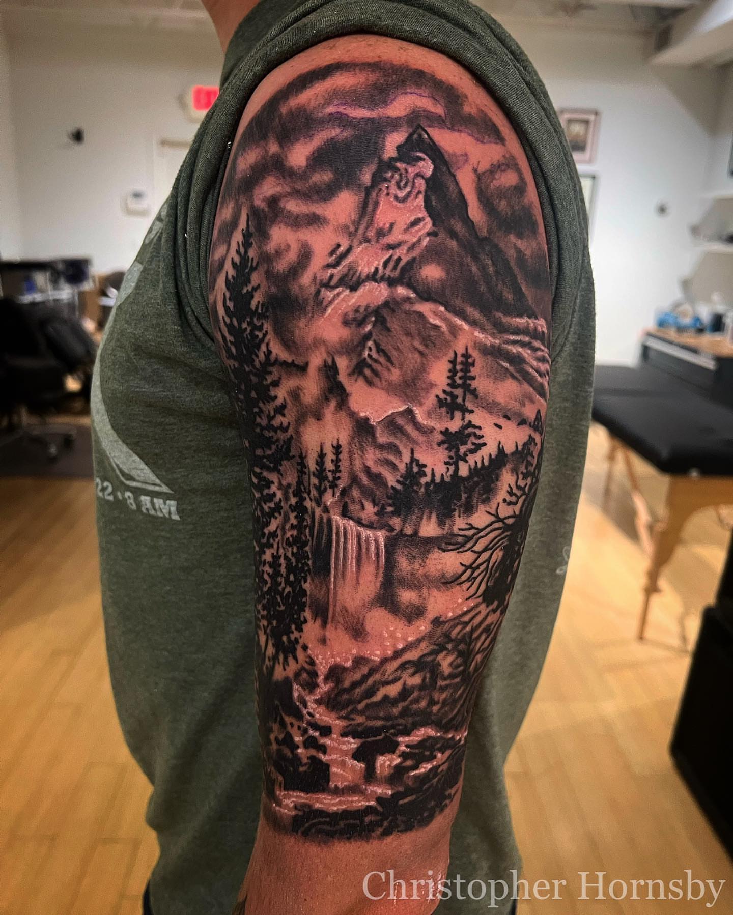 Mountain landscape realism tattoo on the upper arm by Chris Hornsby