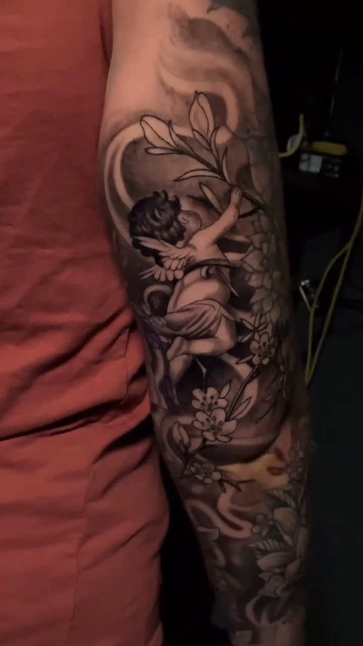 Cherub with flowers and script realism tattoo by Joe Shepp