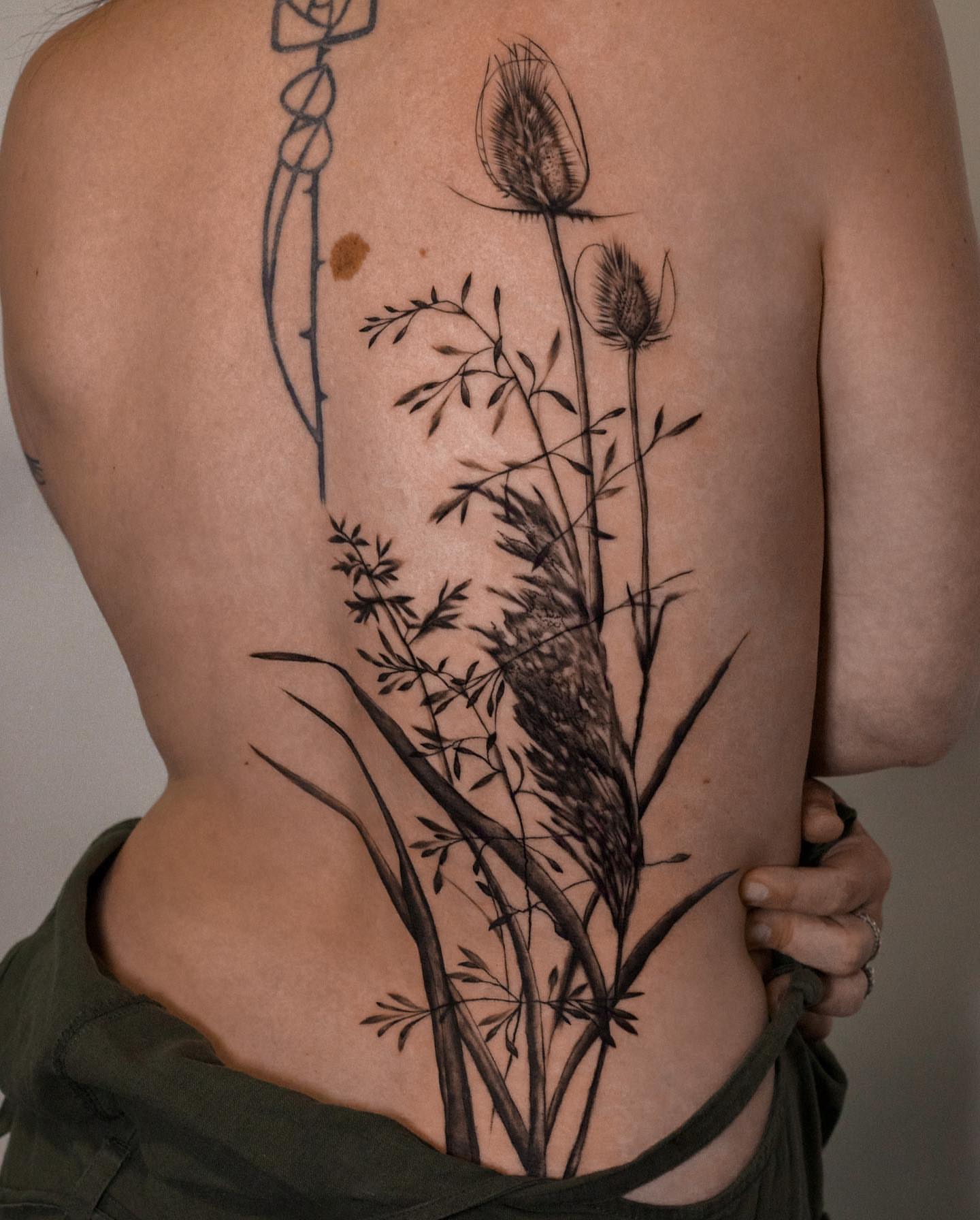 Grass and flowers black and grey tattoo on the back by Alex Suarez