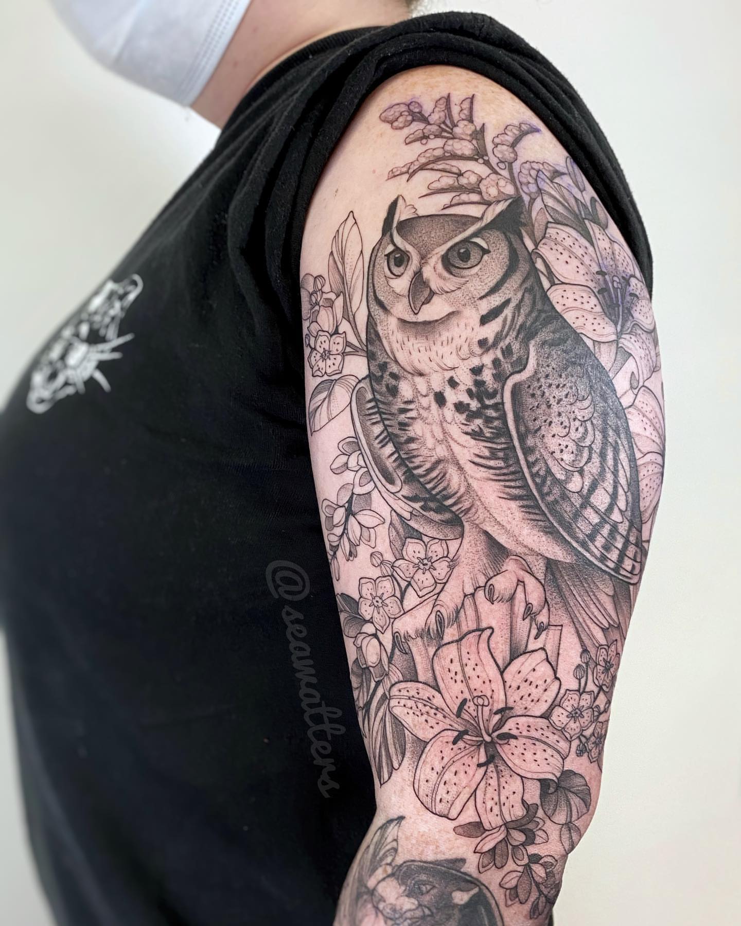 Owl and flowers realism tattoo on the upper arm by Caitlin Watters