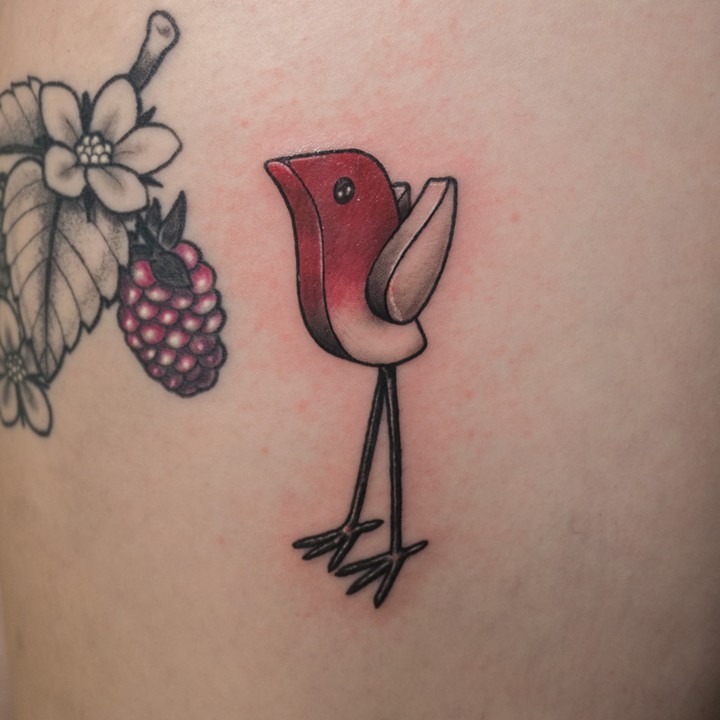 Stylized bird ignorant tattoo on the upper arm by Donald Voelker