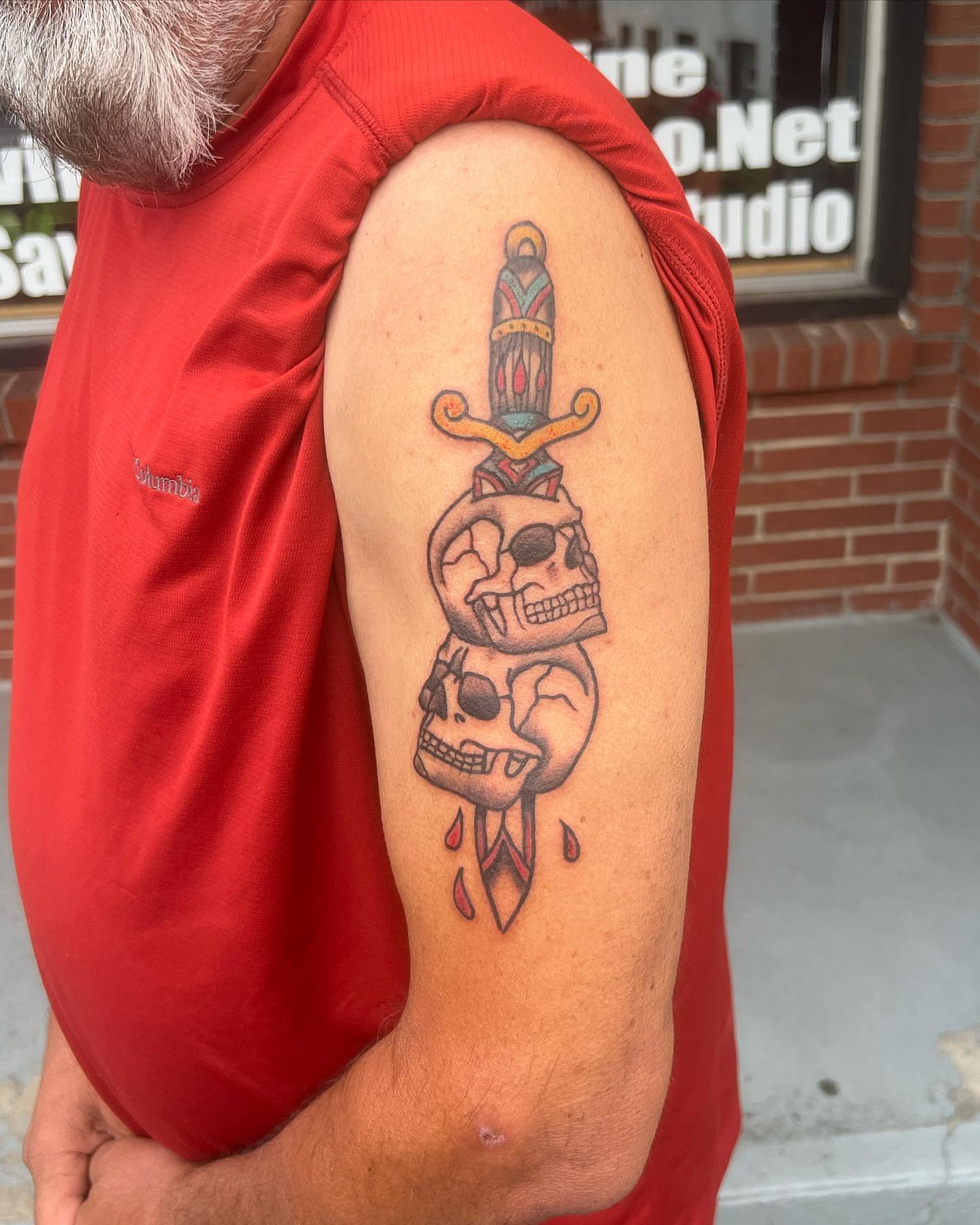 Skulls and dagger American traditional tattoo on the upper arm by Emmy