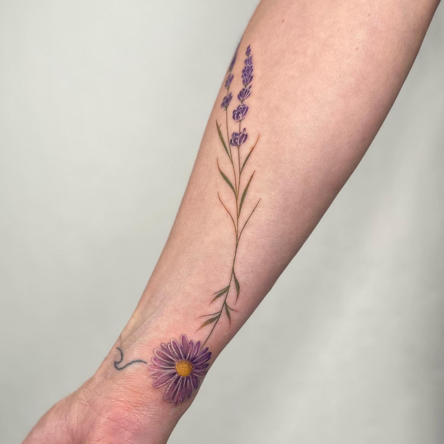 Purple flowers realism tattoo on the forearm by Riki