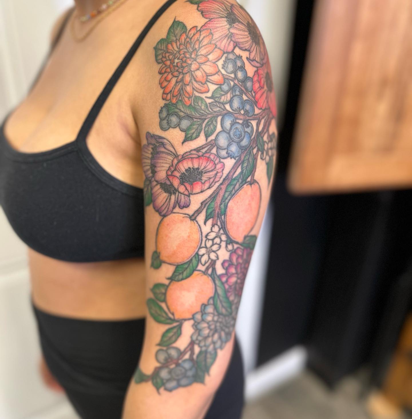 Fruit and floral arrangement new school tattoo on the upper arm by 𝕵𝖊𝖘𝖘𝖆 𝕭𝖎𝖌𝖊𝖑𝖔𝖜, Harrison, New Jersey