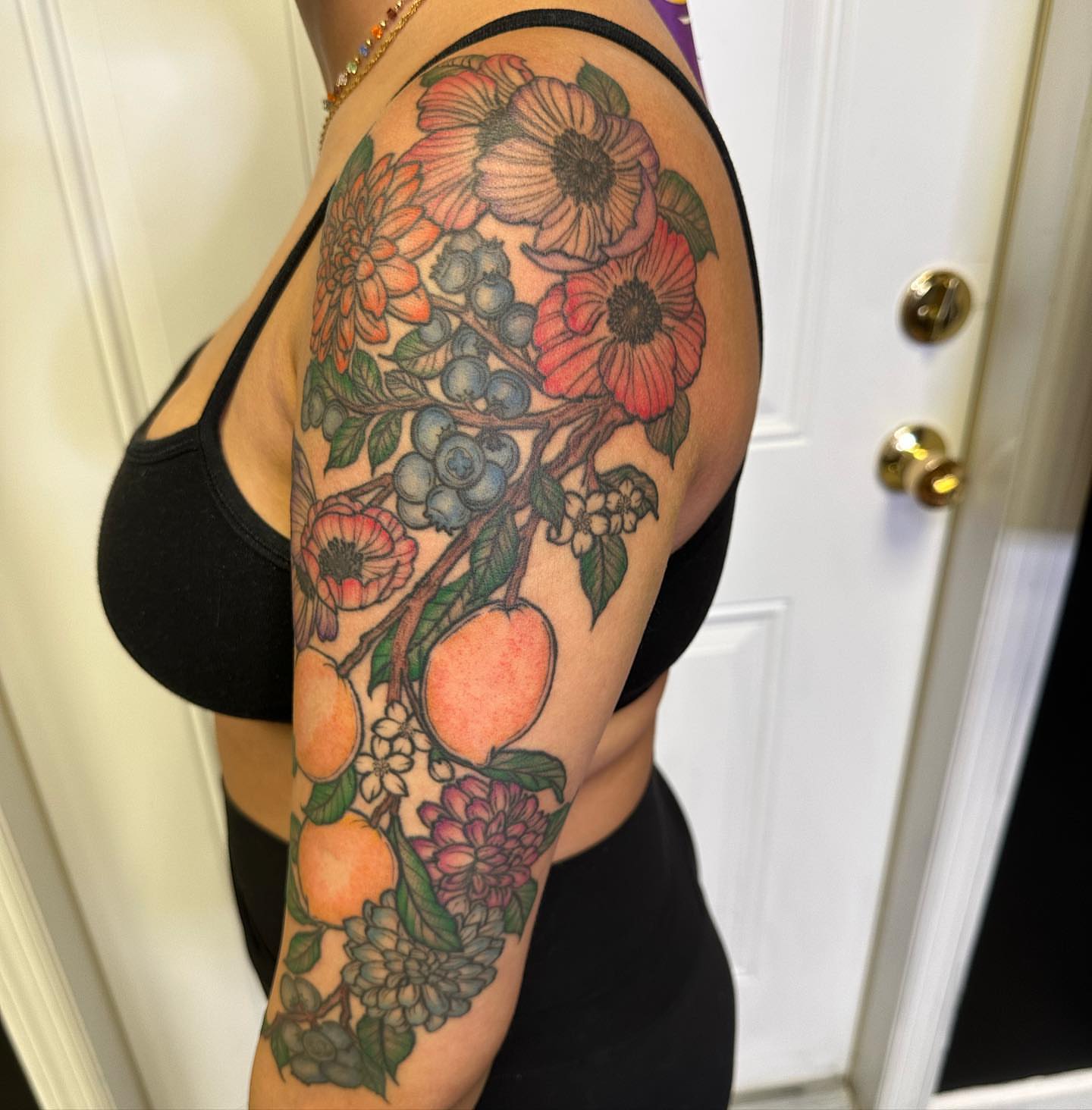 Fruit and floral bouquet new school tattoo on the upper arm by 𝕵𝖊𝖘𝖘𝖆 𝕭𝖎𝖌𝖊𝖑𝖔𝖜, Harrison, New Jersey