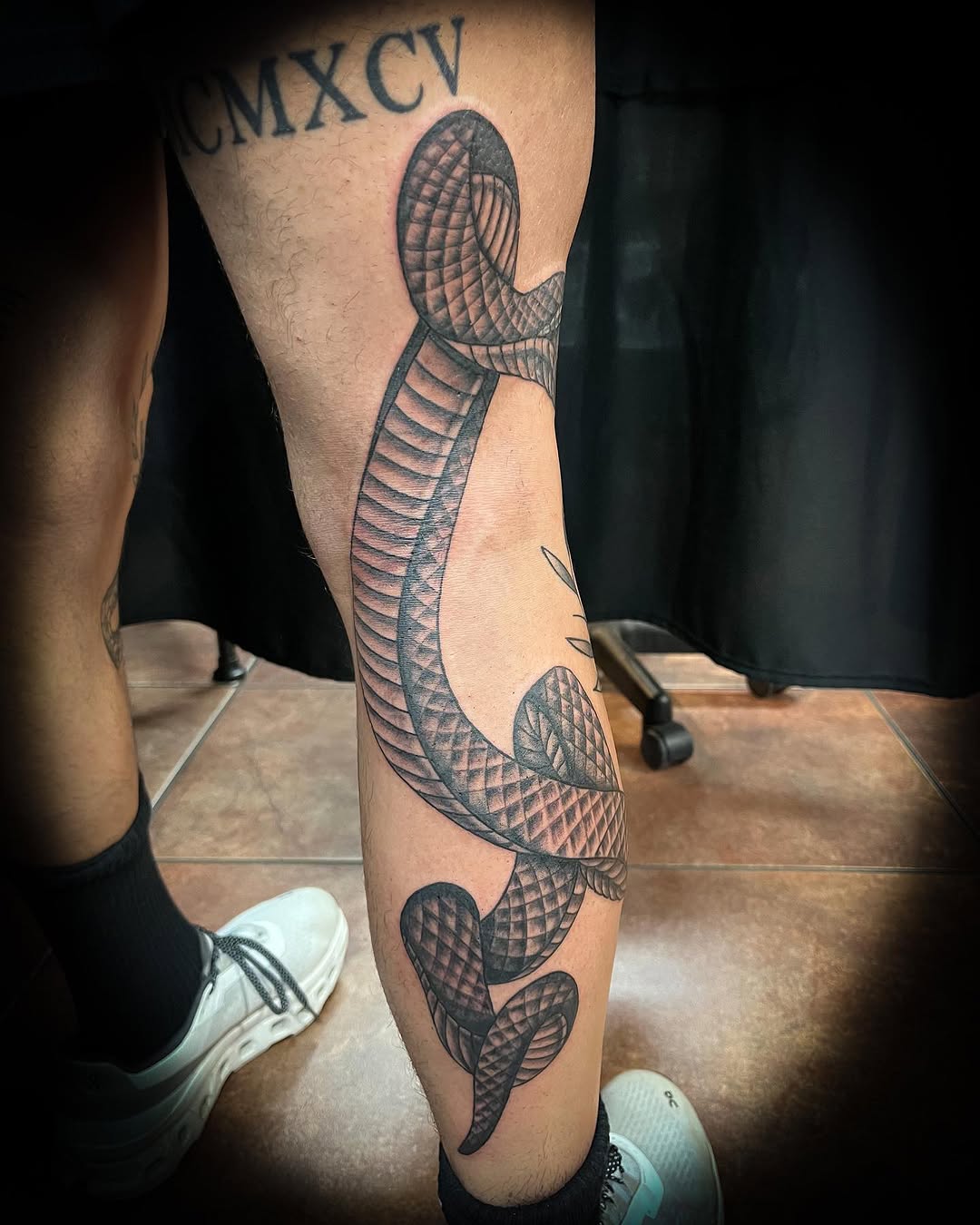 Snake wrapped around leg surrealism tattoo on the calf by Melissa Peña NYC