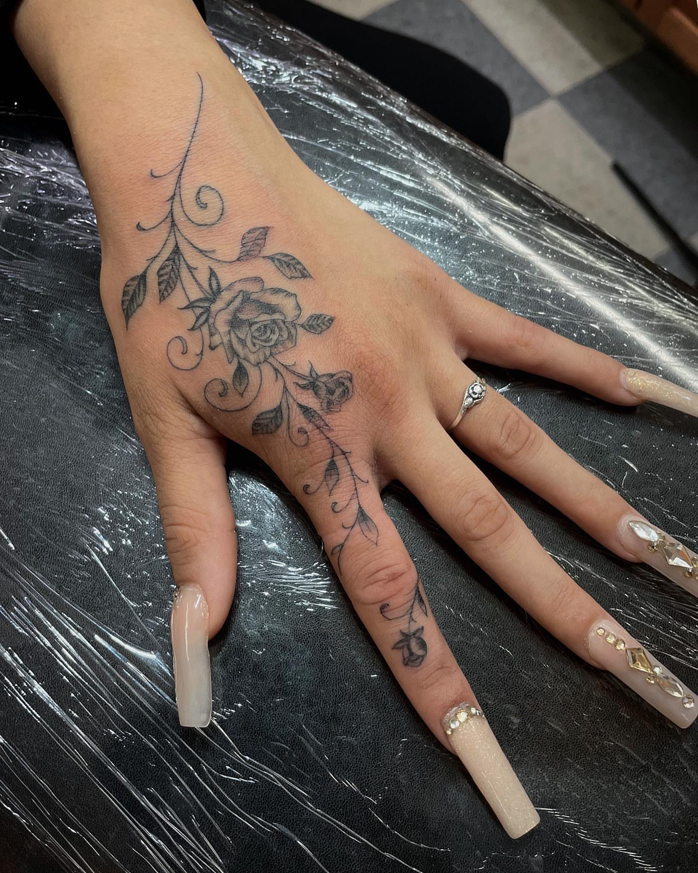 Rose and vine black and grey tattoo on the hand by Manny