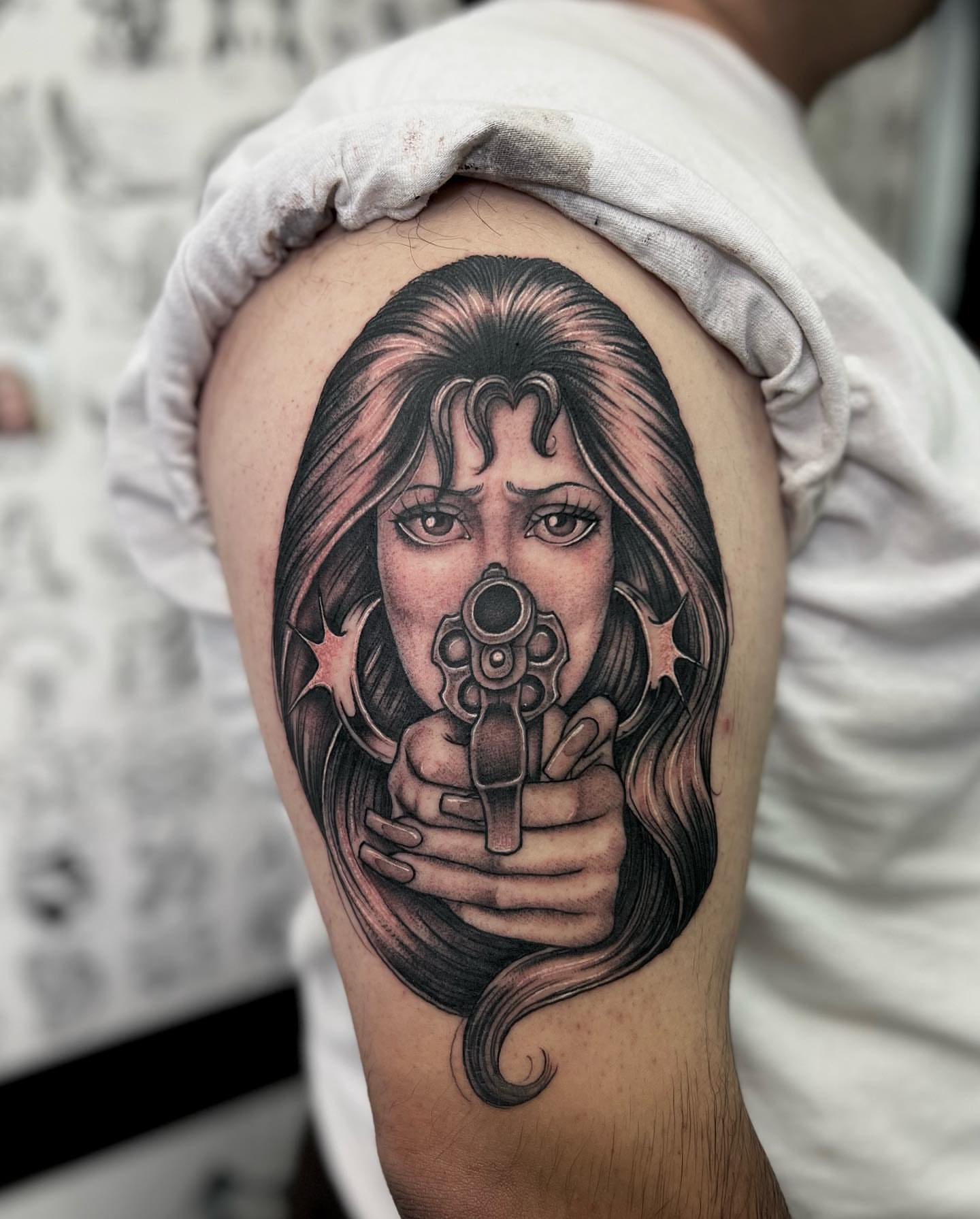 Gun-wielding woman realism tattoo on the shoulder by Valerie Dominguez