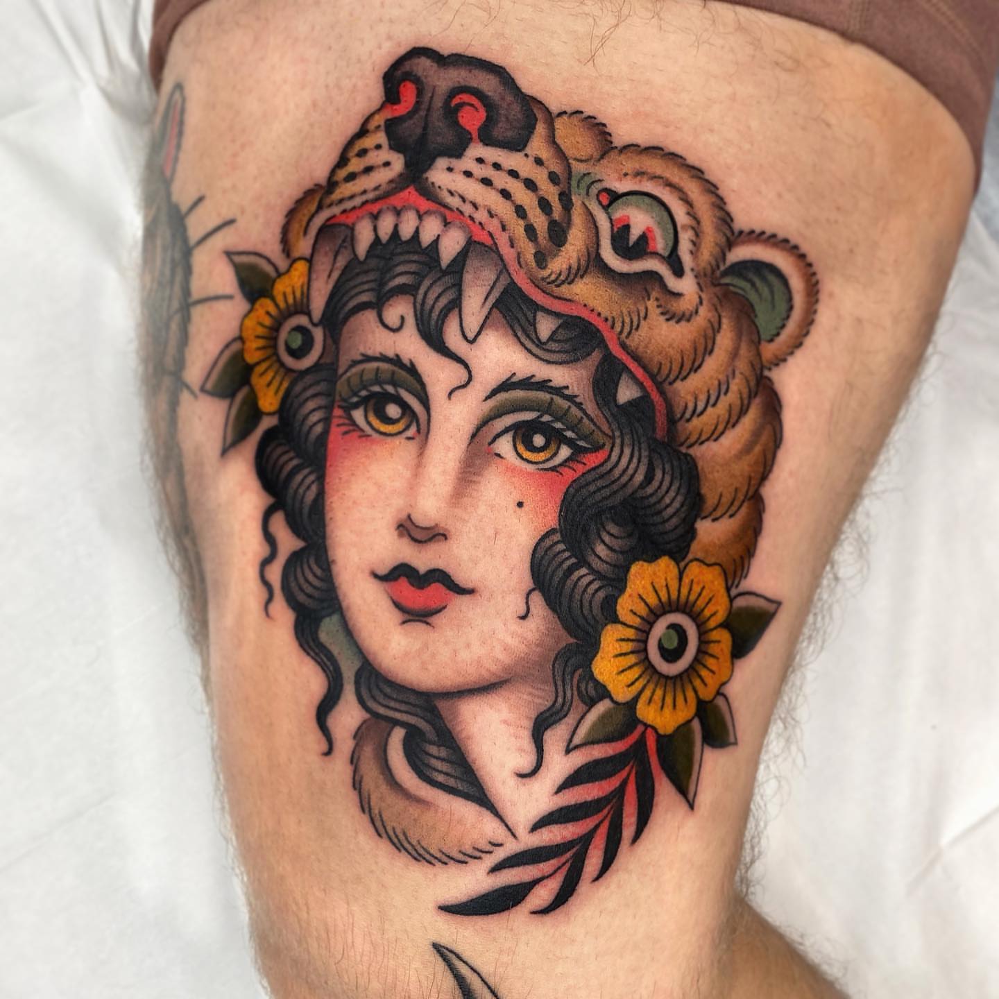 Woman with lion head American traditional tattoo on the thigh by Wes Hoffman