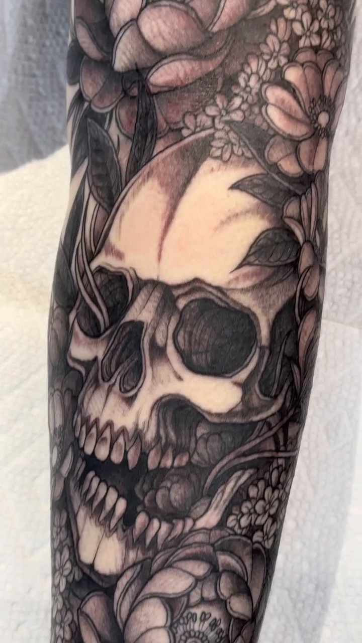 Skull and flowers sleeve realism tattoo on the forearm by 🦎Langley Osborn Tattoos🦎, Maryville, Tennessee