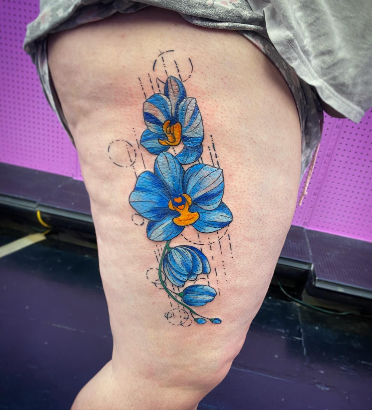 Blue orchids watercolor tattoo on the thigh by Sally Darling