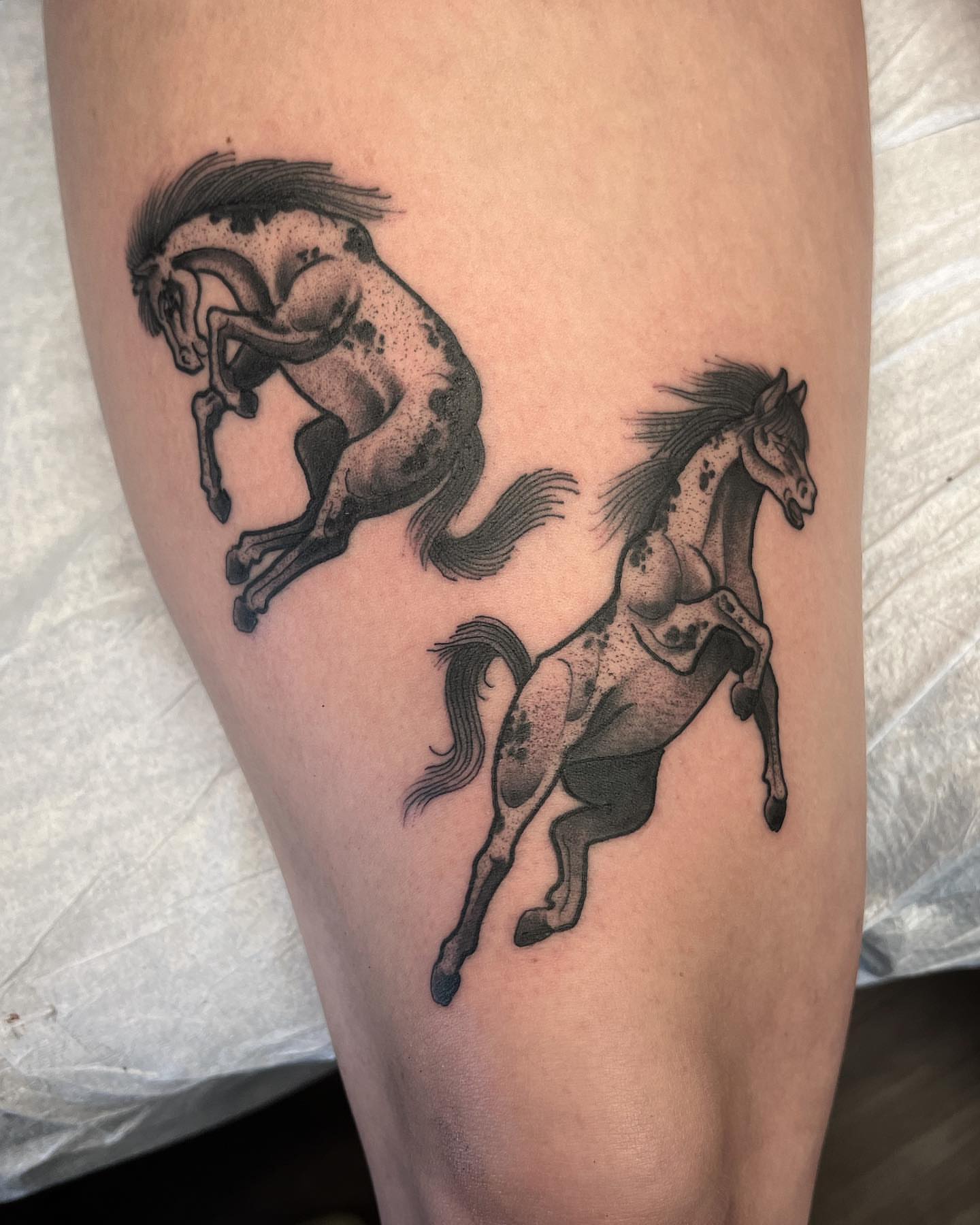 Horses black and grey tattoo on the thigh by Daniel Patrick