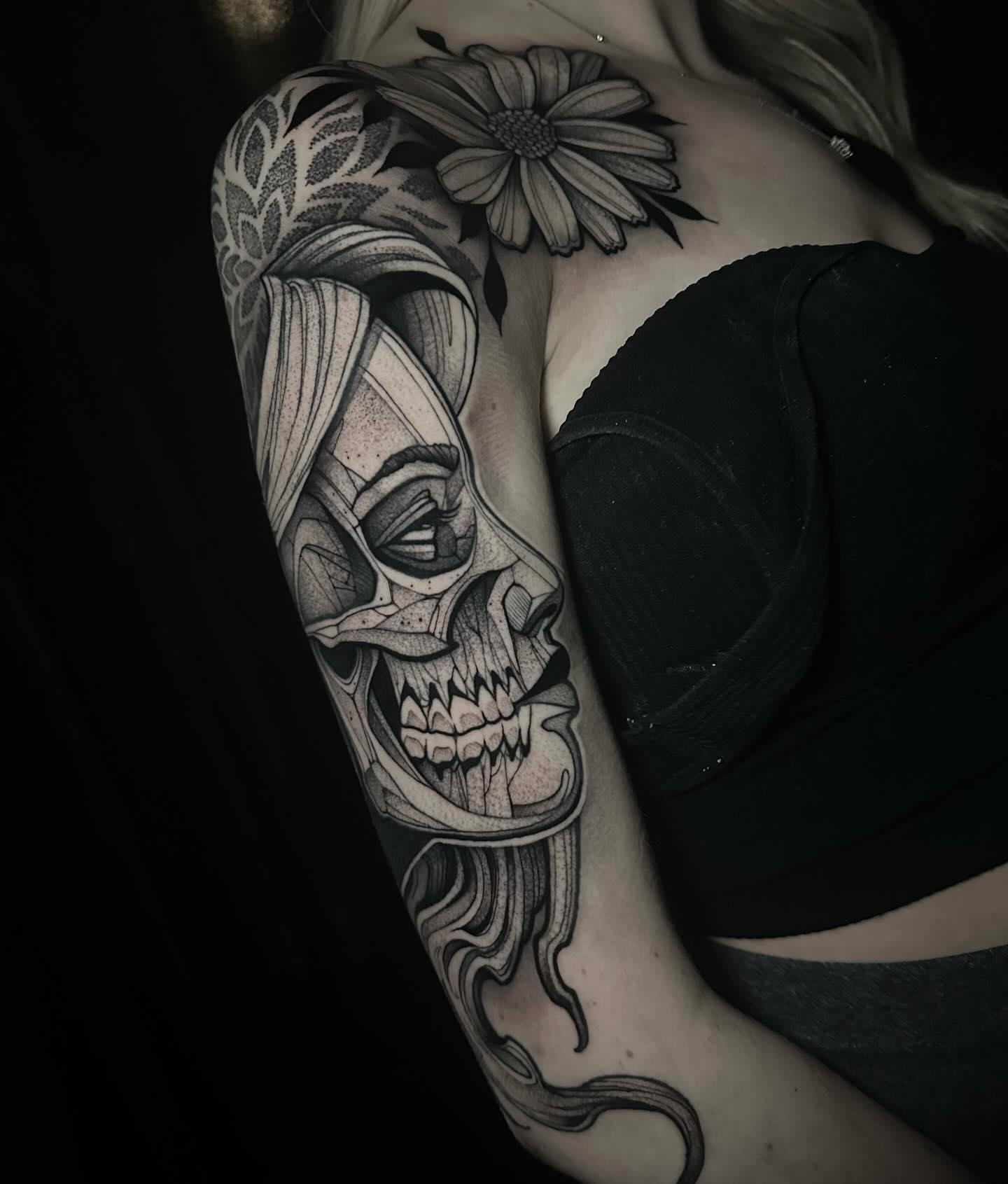 Skull with flower realism tattoo on the upper arm by Clayton Smith (BEAR)