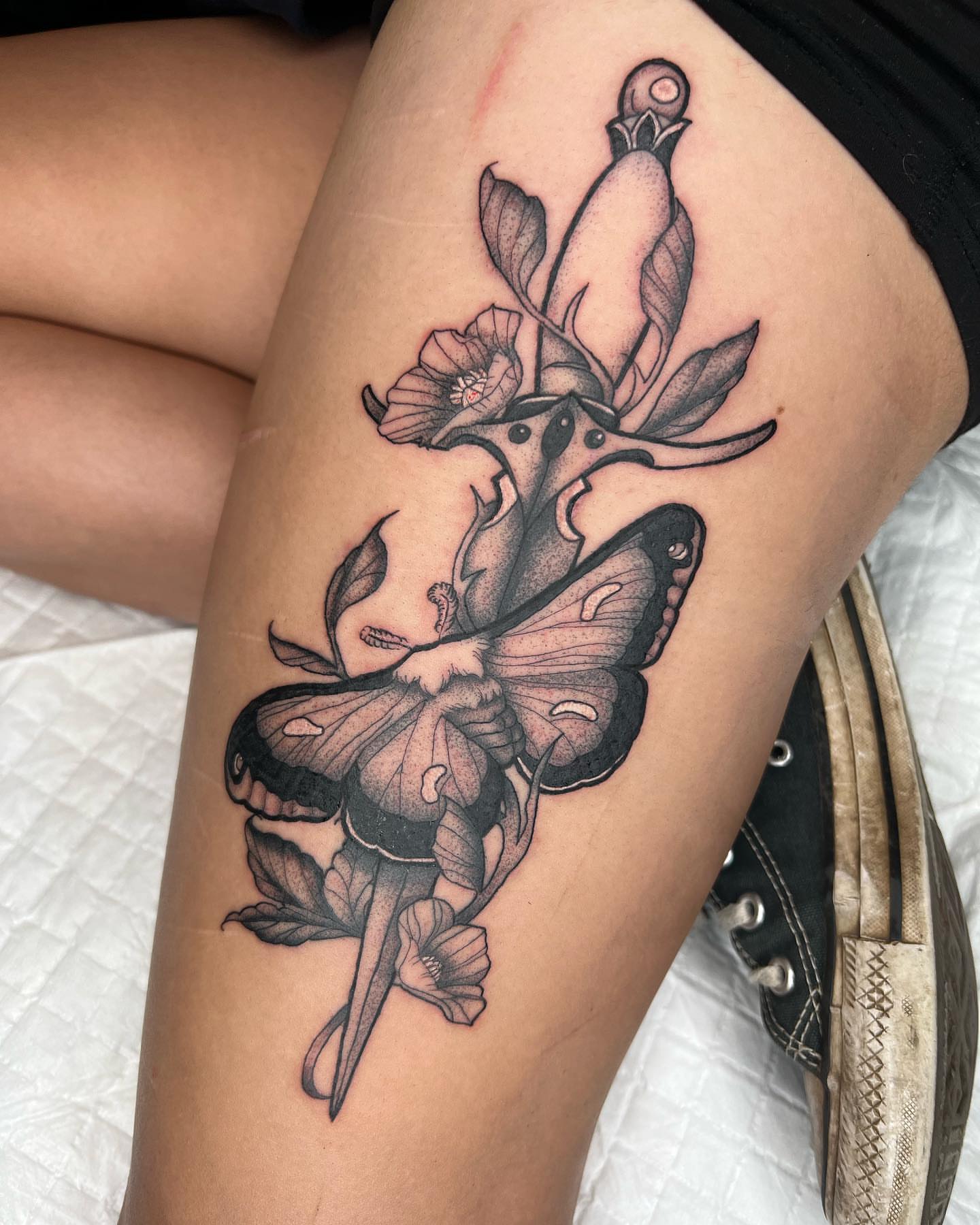 Butterfly and flowers black and grey tattoo on the thigh by Kayla Cordova