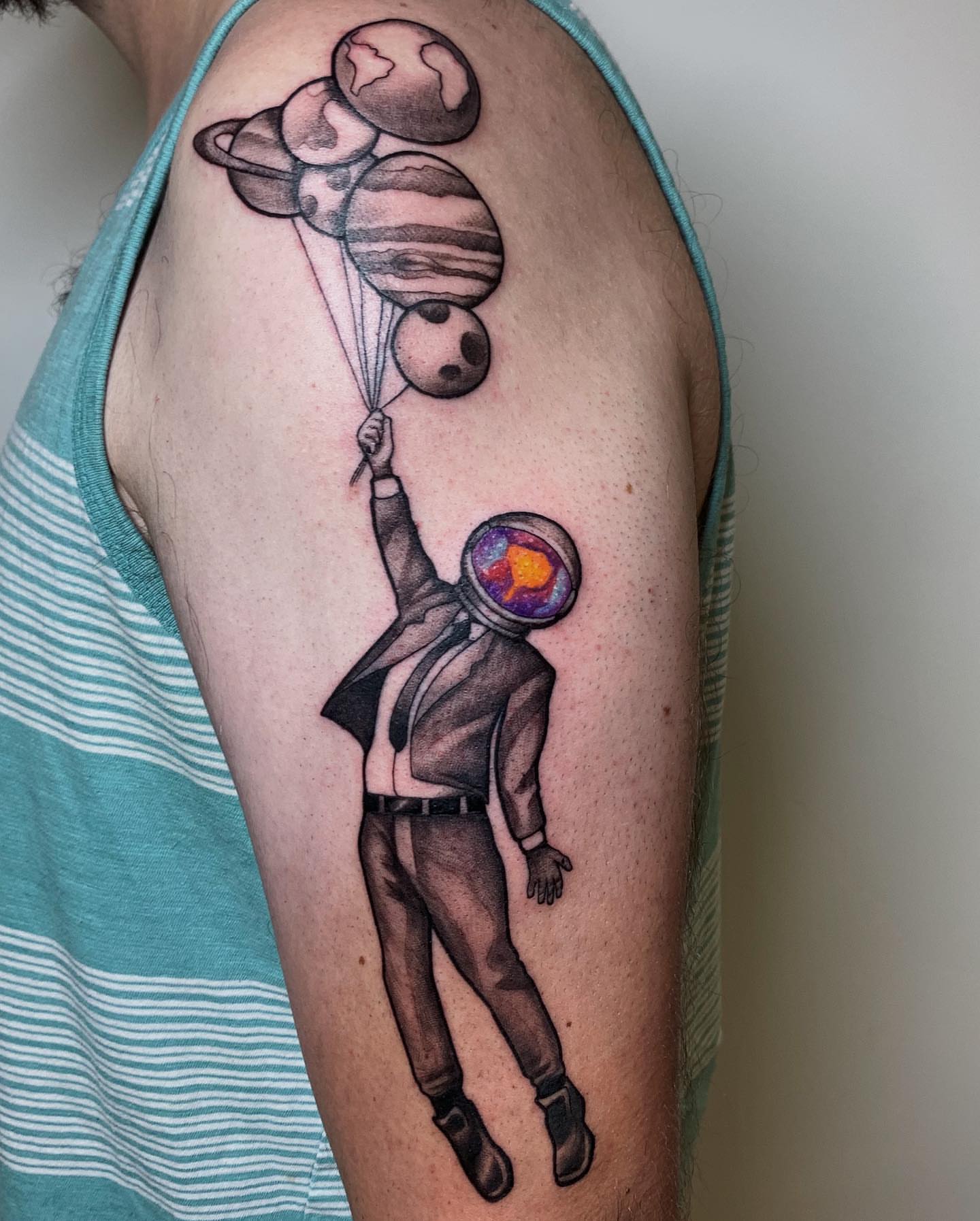 Astronaut with planets realism tattoo on the upper arm by Kolby