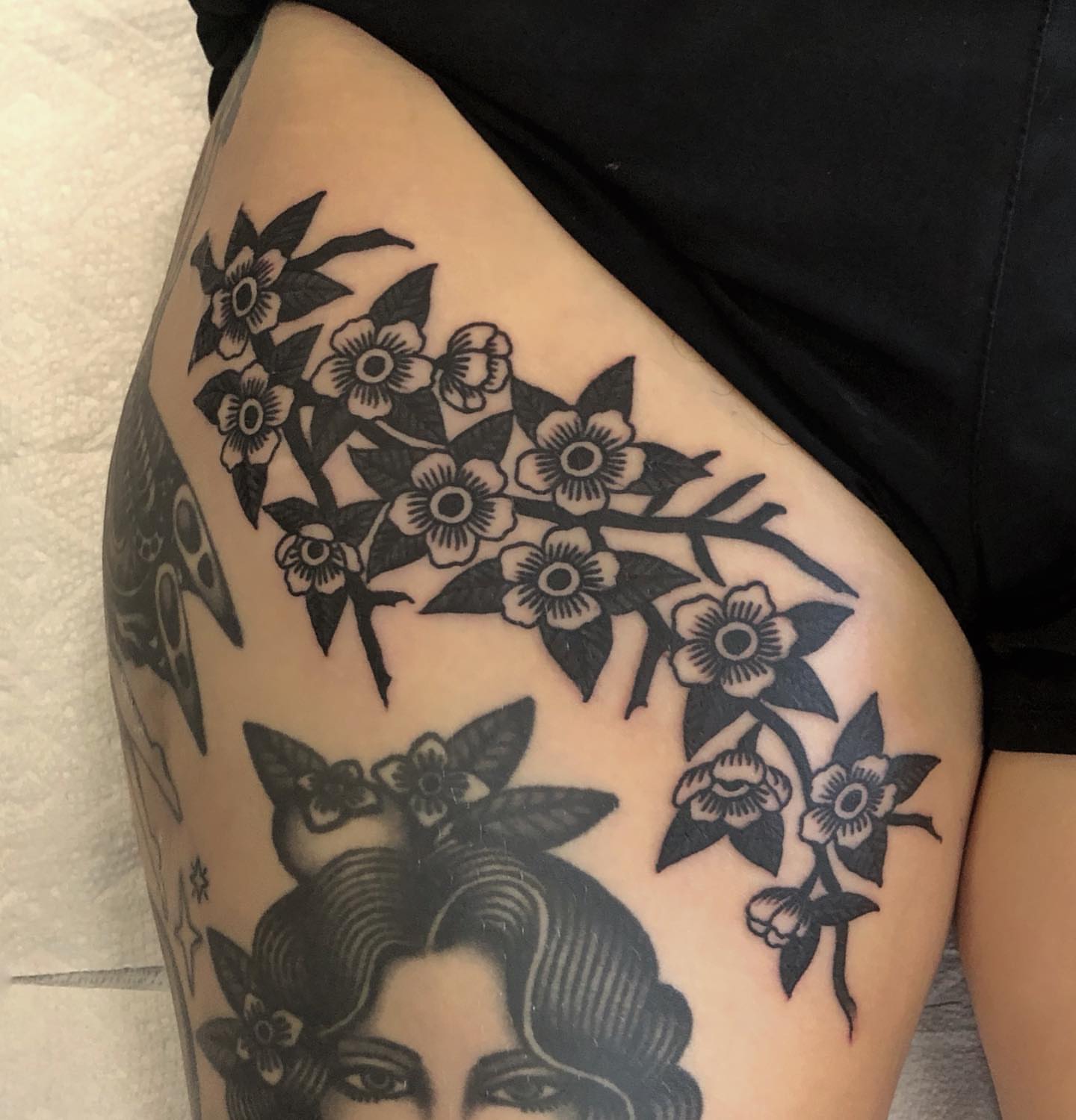 Cherry blossoms black and grey tattoo on the thigh by Ben Fiedler