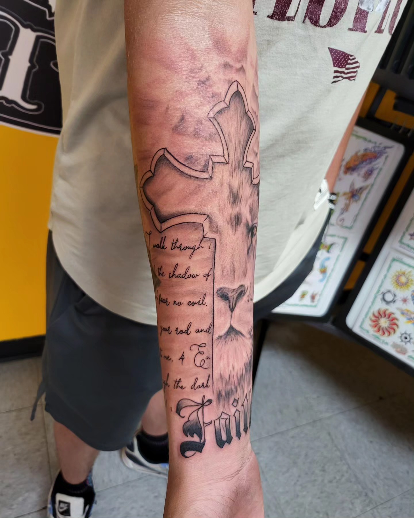 Cross with lion black and grey tattoo on the forearm by Mike Stamper