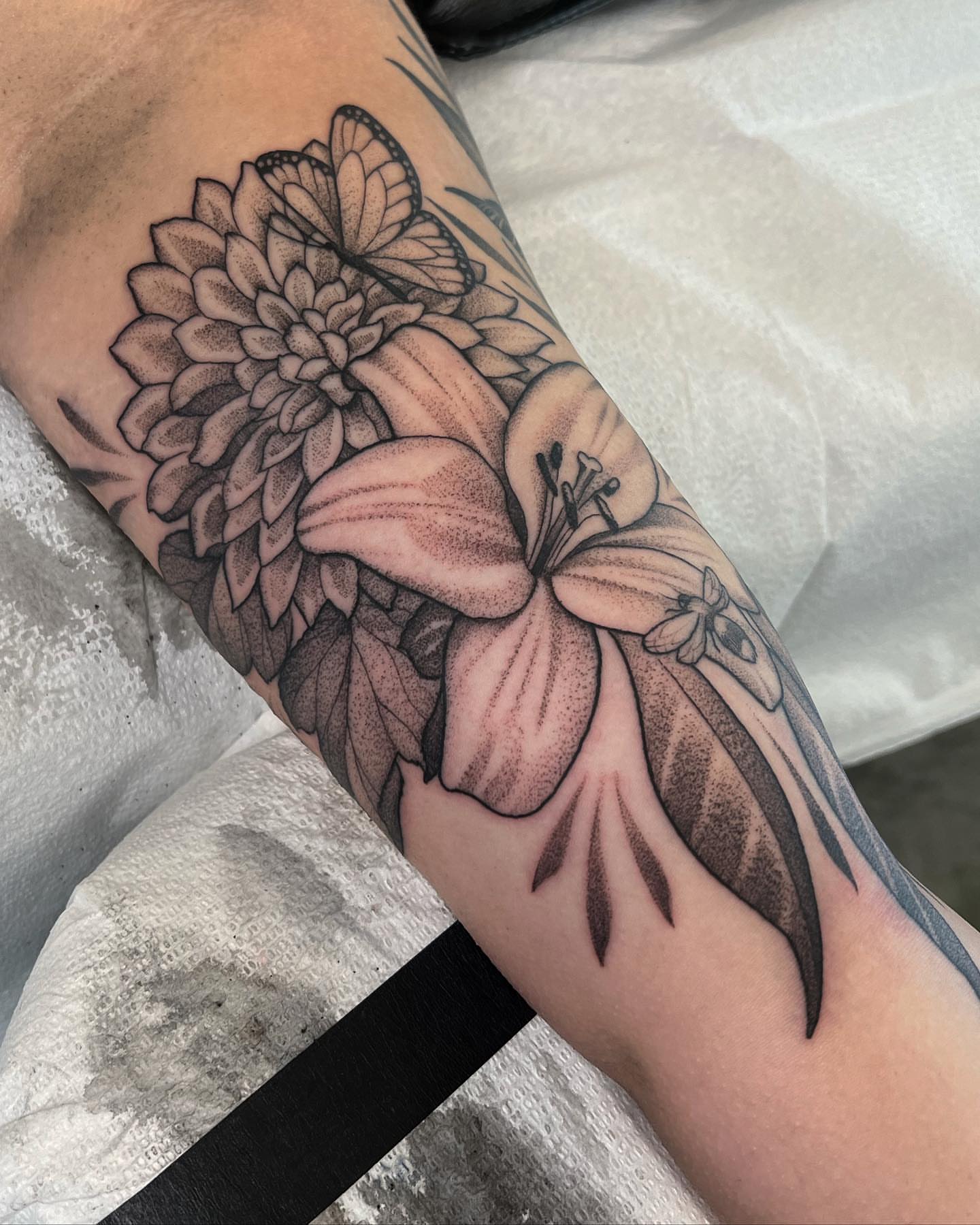 Flower and butterfly realism tattoo on the forearm by Will Campbell