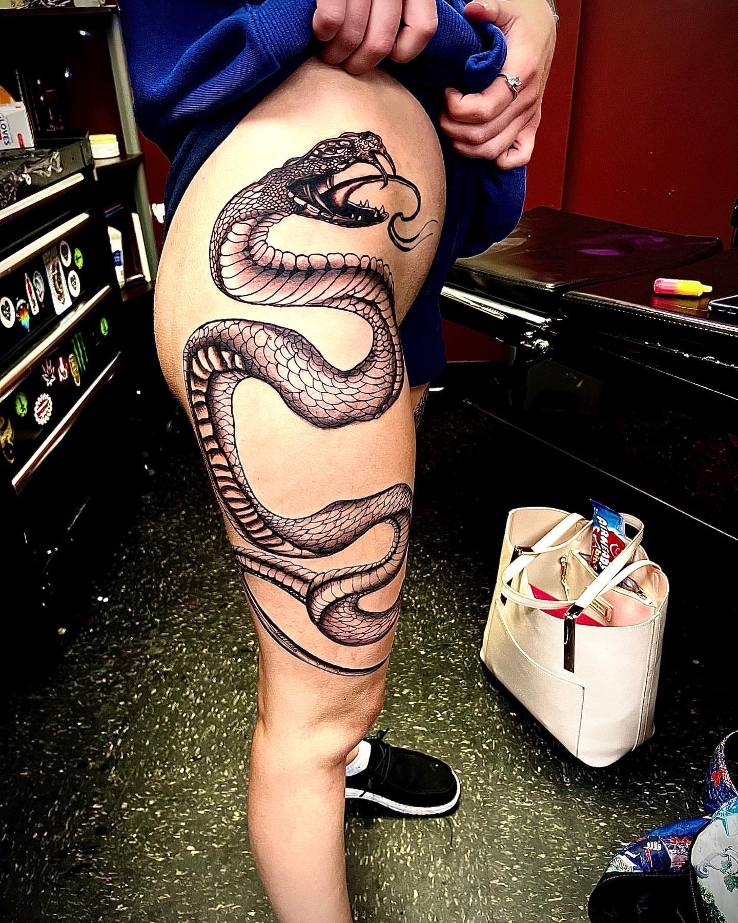 Snake black and grey tattoo on the thigh by Alyssa Turner