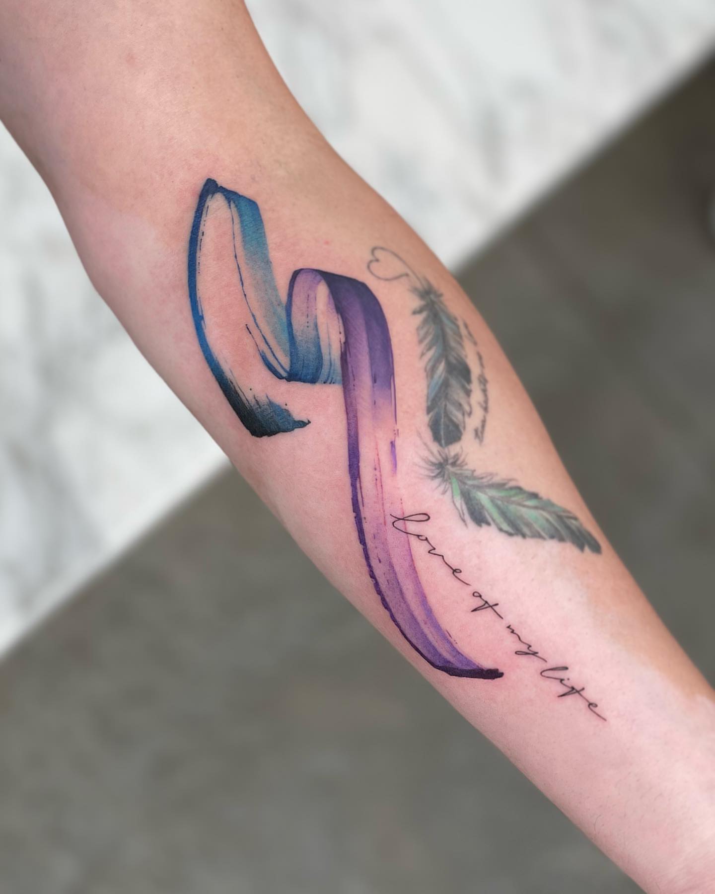 Brushstroke and feathers watercolor tattoo on the forearm by Georgia Grey