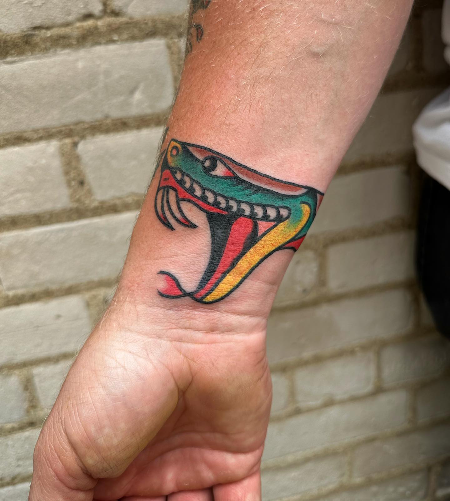 Snake American traditional tattoo on the forearm by Isaac Brethauer