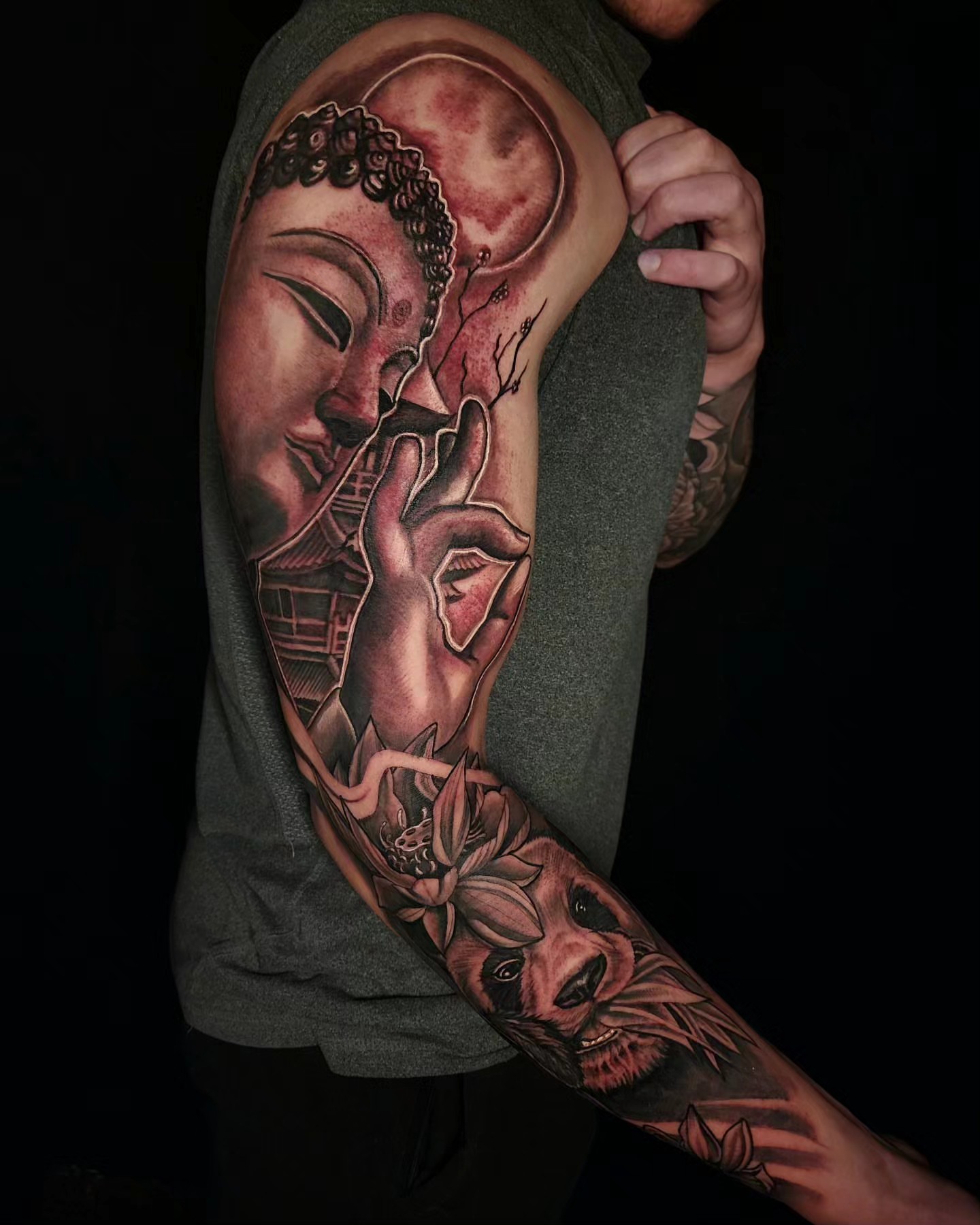 Buddha head and lion realism tattoo on the upper arm by Tyler Cromwell
