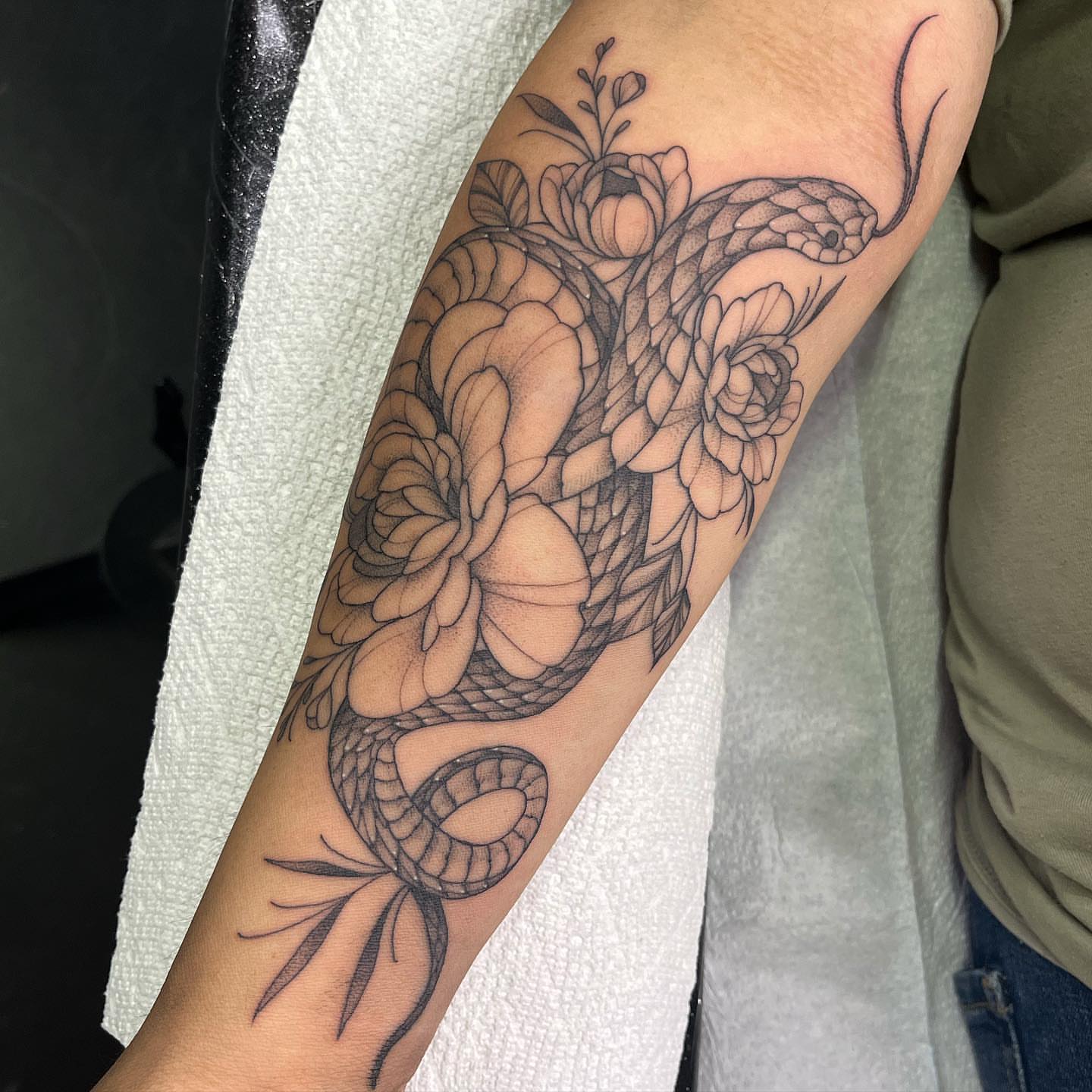 Snake and flowers dotwork tattoo on the forearm by liliana lopez
