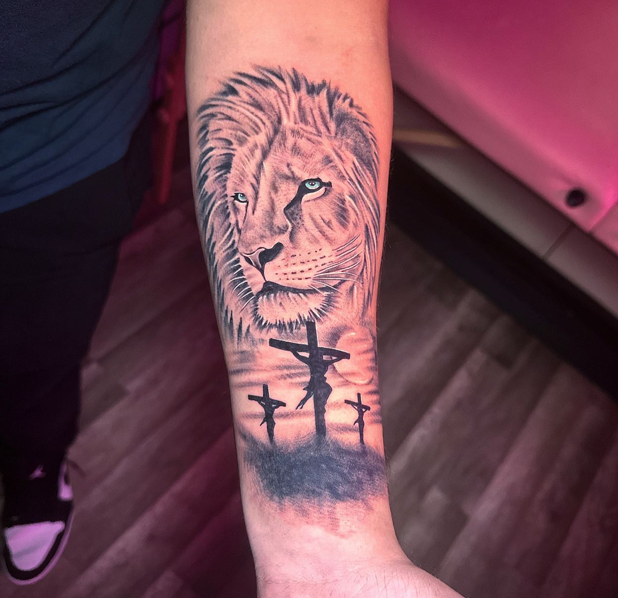 Lion and crucifixion realism tattoo on the forearm by Diana Kunz