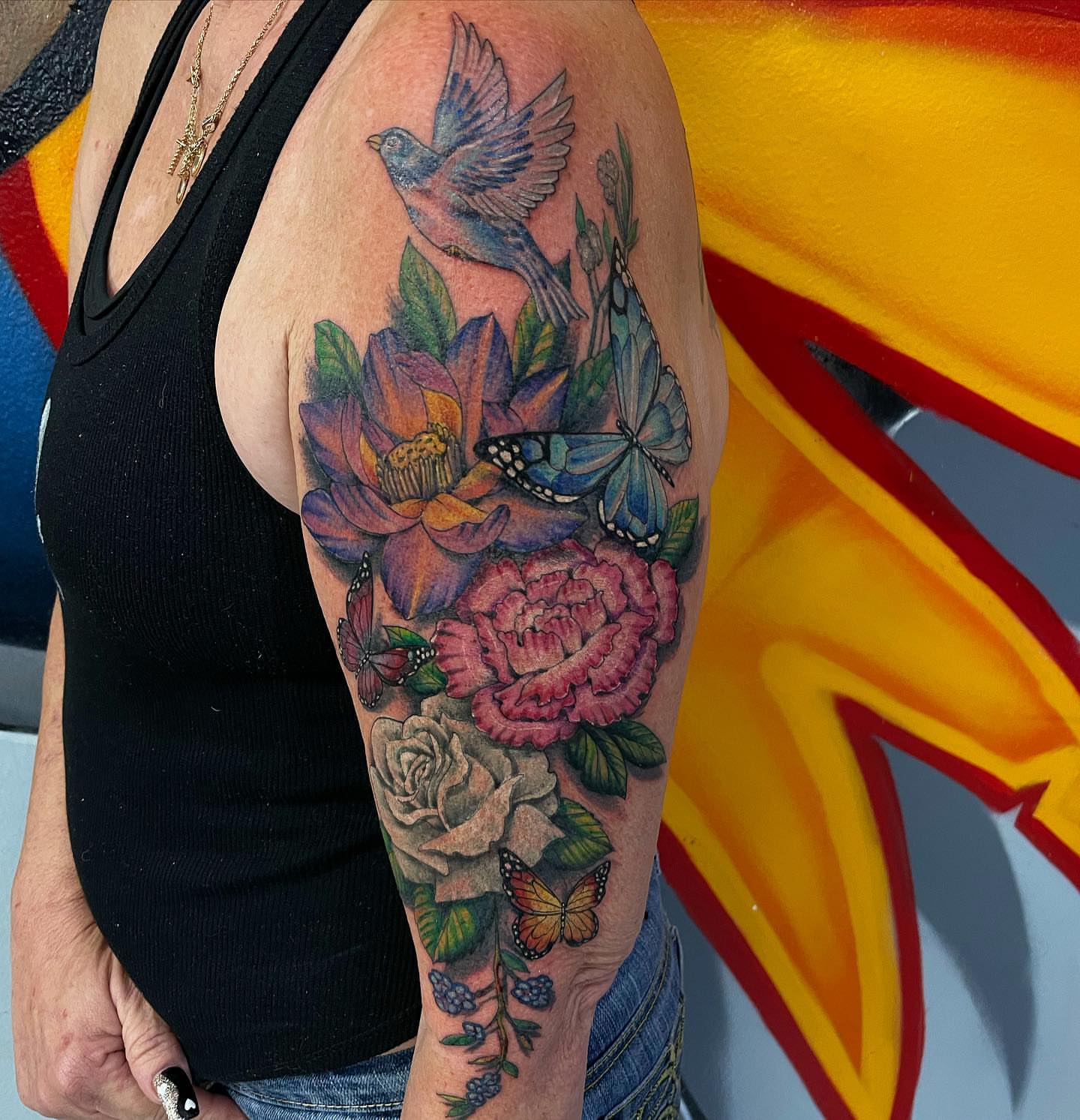 Floral bouquet realism tattoo on the upper arm by Manny