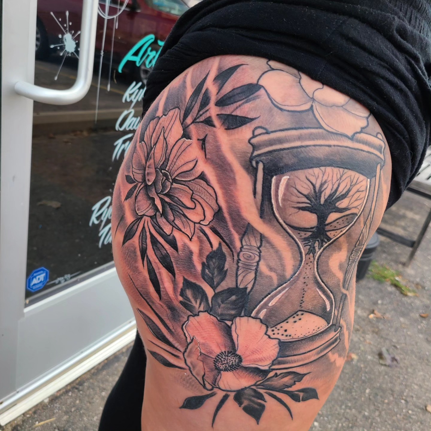 Hourglass and flowers realism tattoo on the thigh by David Johnson