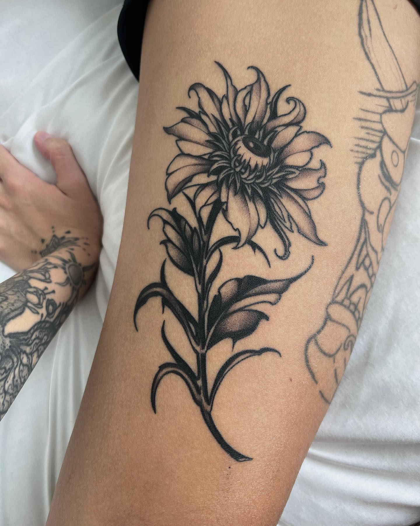 Sunflower black and grey tattoo on the thigh by Bruna Bianculli