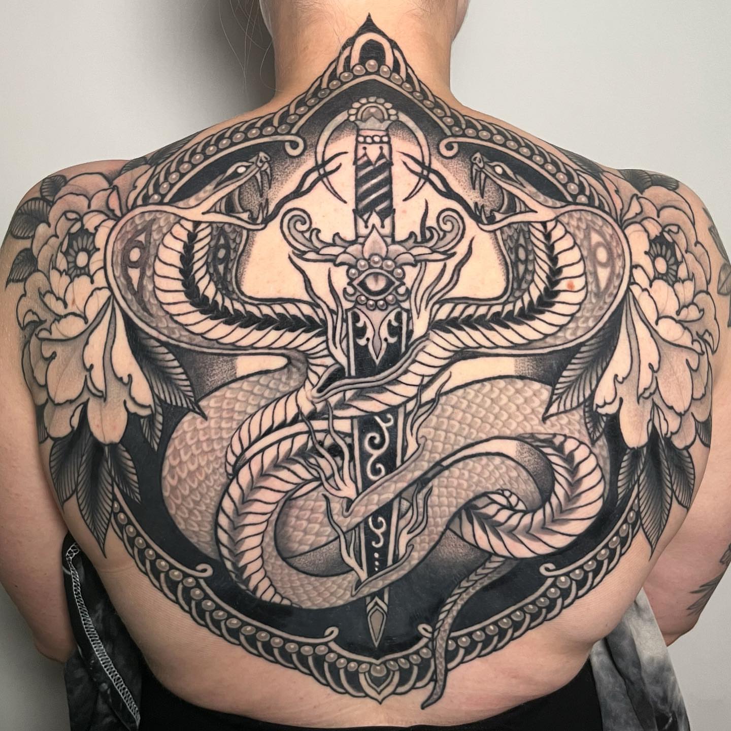 Snake and cross geometric tattoo on the back by Sara Lewis