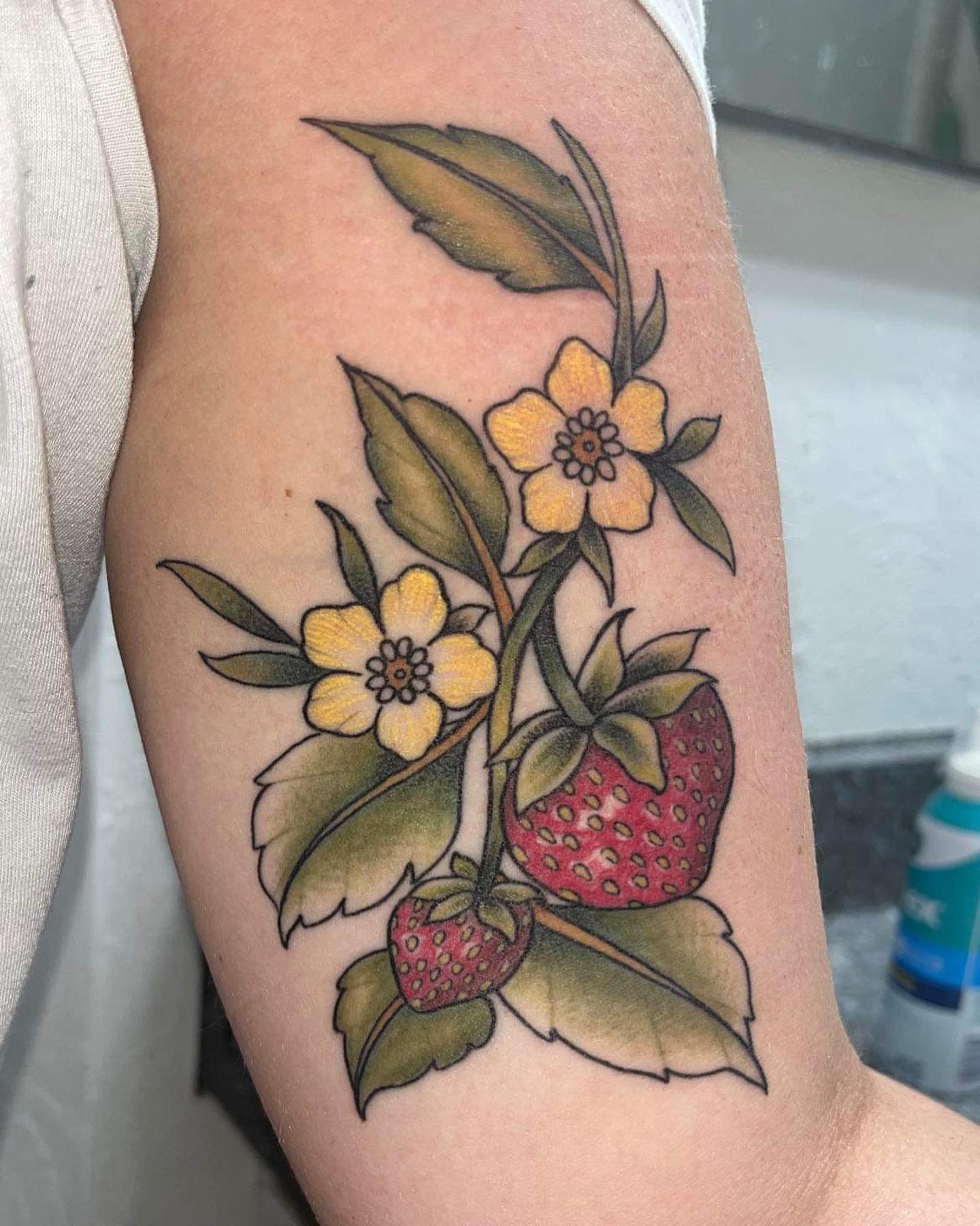 Strawberry and flowers realism tattoo on the forearm by Abel Ponce