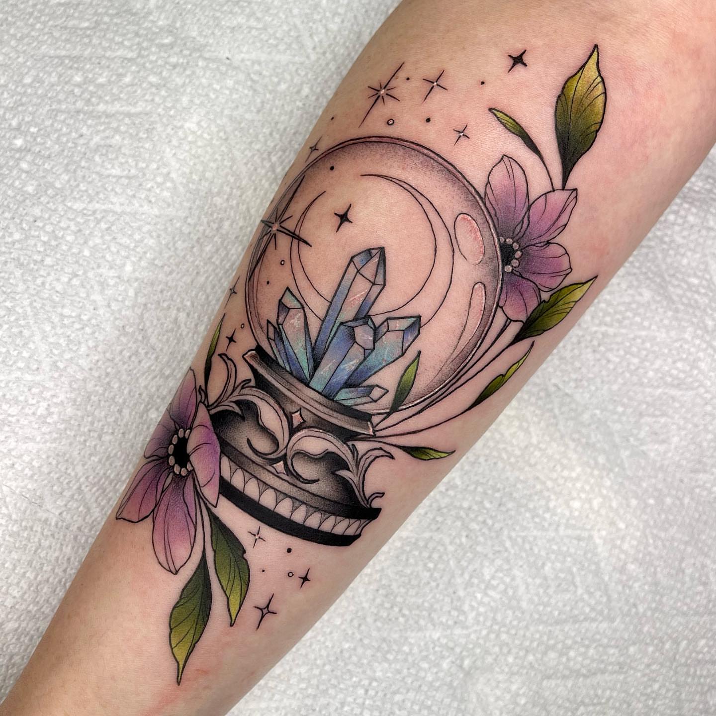 Crystal ball with flowers American traditional tattoo on the forearm by Lexx Christine